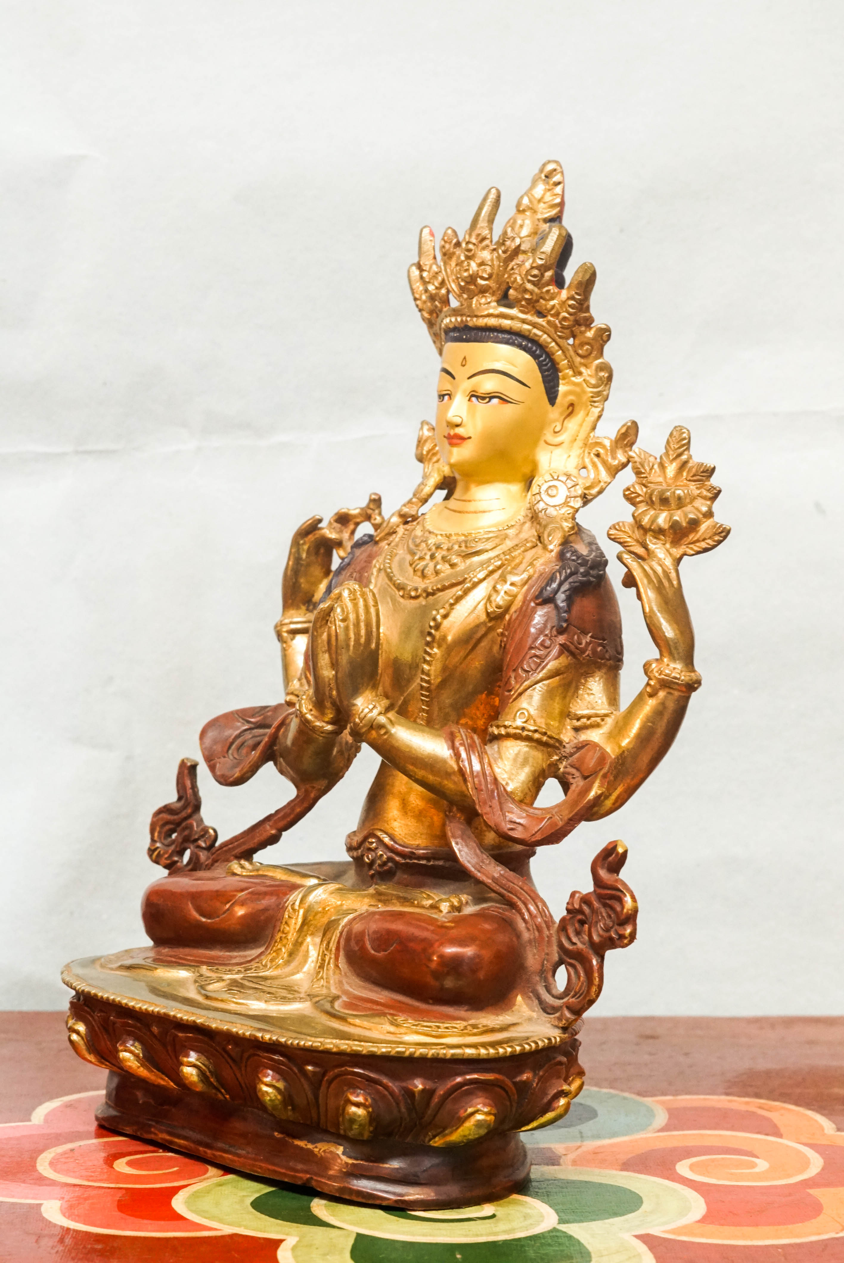 Intricately carved Avalokiteshvara (Chenrezig) statue seated on a lotus pedestal, with multiple arms representing boundless compassion and the ability to assist countless beings simultaneously.