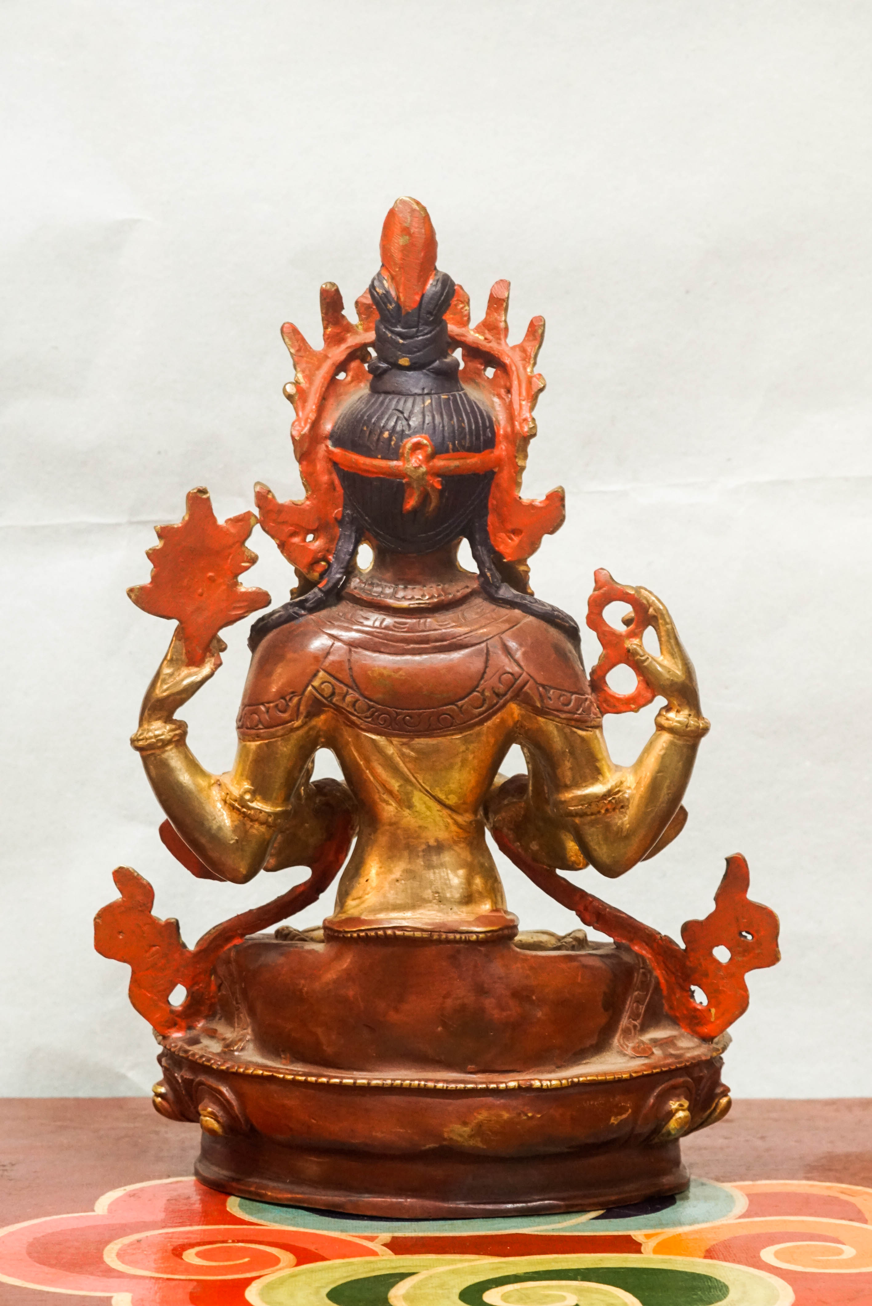 Intricately carved Avalokiteshvara (Chenrezig) statue seated on a lotus pedestal, with multiple arms representing boundless compassion and the ability to assist countless beings simultaneously.