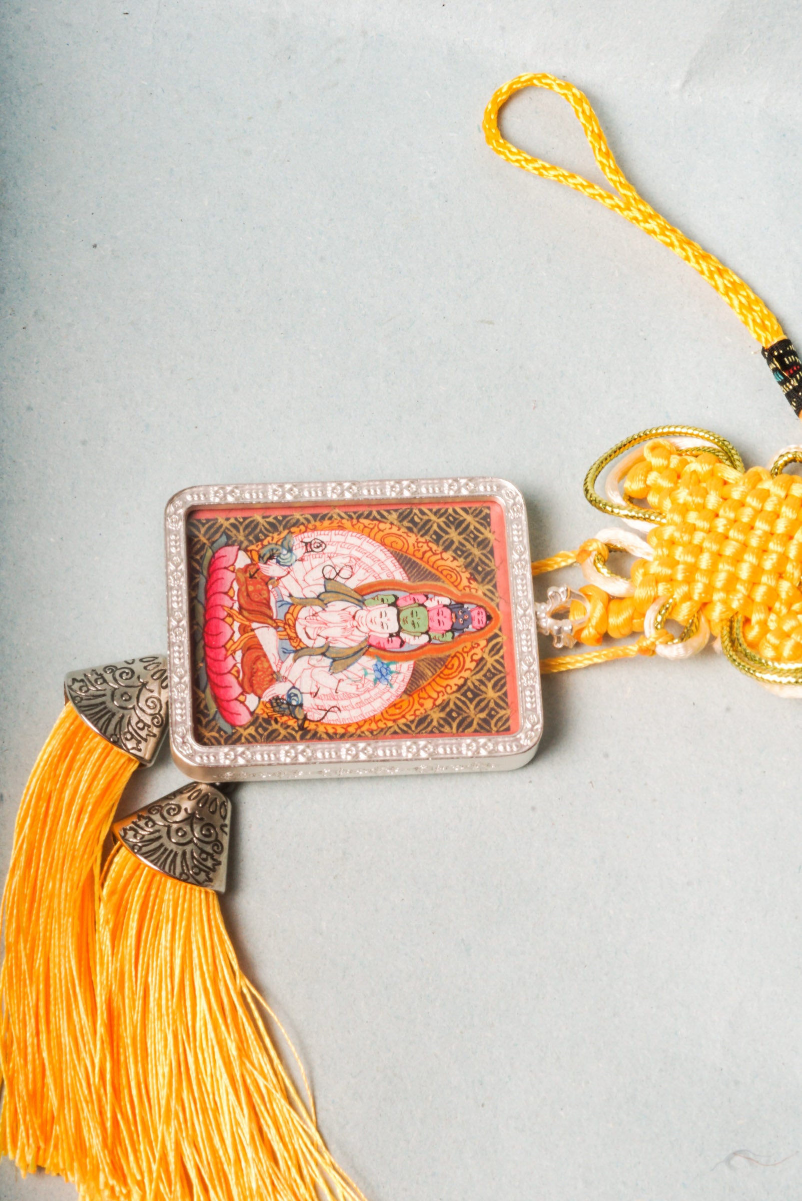 The Avalokiteshvara Ghau Thangka depicts the compassionate Bodhisattva with multiple arms and heads, symbolizing his boundless ability to help all beings. Hand-painted with natural pigments, this portable Thangka serves as a powerful amulet for protection, guidance, and spiritual growth.