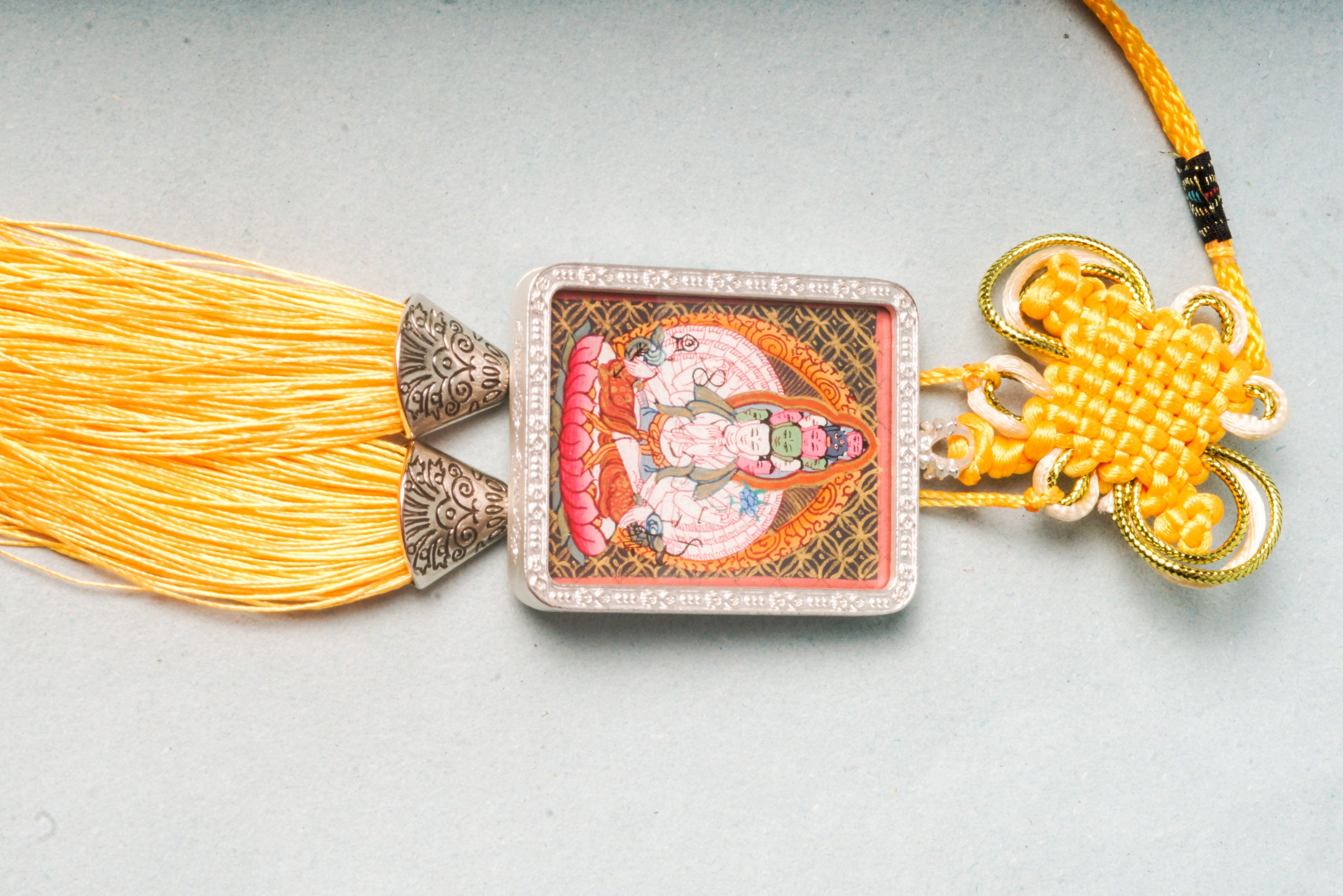 The Avalokiteshvara Ghau Thangka depicts the compassionate Bodhisattva with multiple arms and heads, symbolizing his boundless ability to help all beings. Hand-painted with natural pigments, this portable Thangka serves as a powerful amulet for protection, guidance, and spiritual growth.