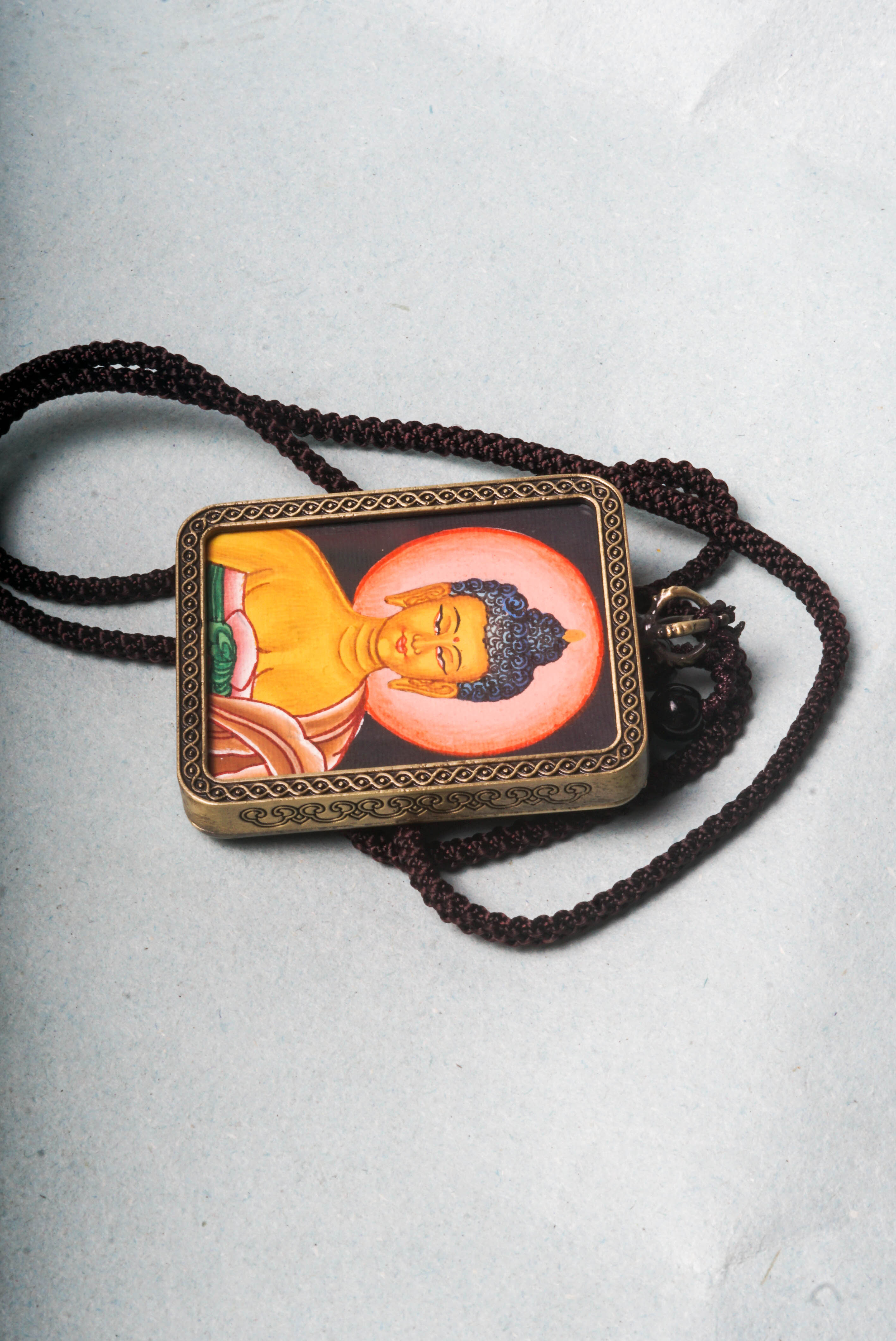 This Buddha Ghau Thangka captures the serene wisdom and compassion of the Buddha in a detailed, hand-painted portrait using natural mineral pigments.