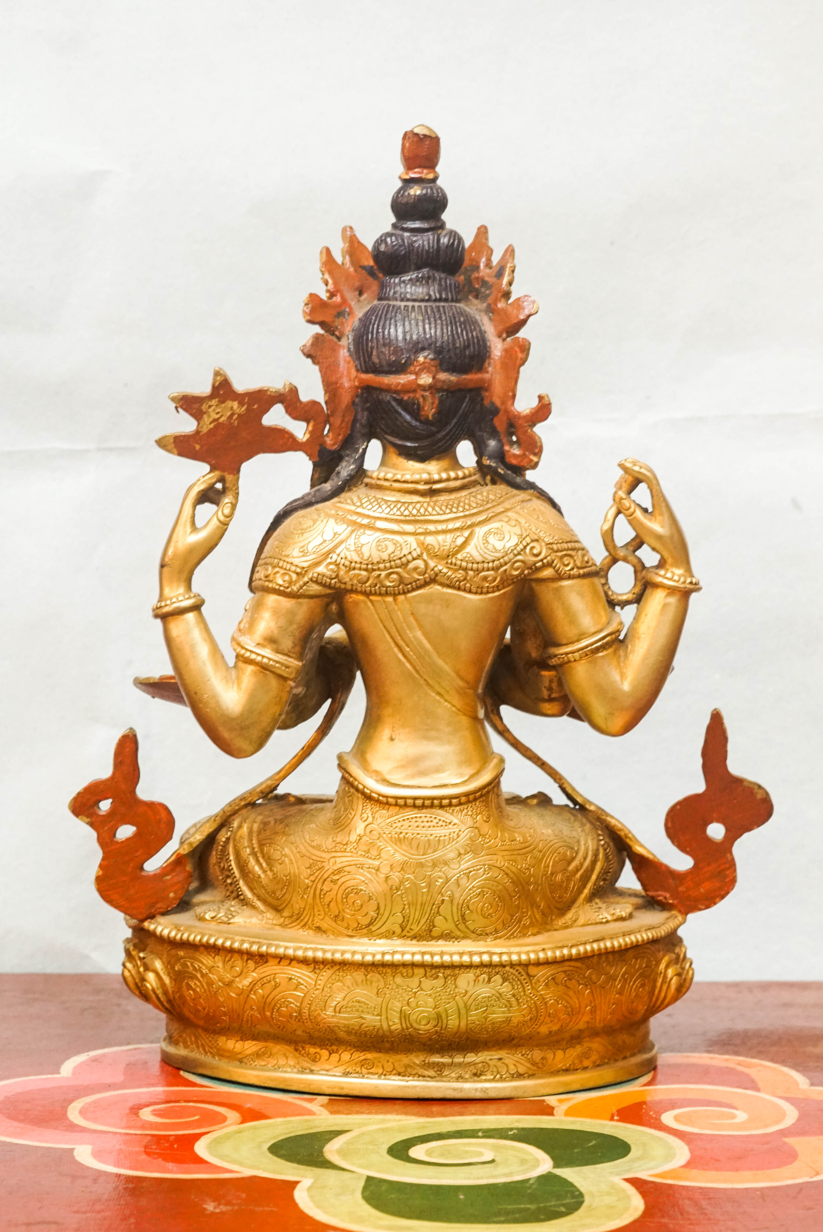A detailed depiction of Chenrezig, seated in meditation, with multiple arms, holding a lotus flower and prayer beads, representing his vow to relieve the suffering of all beings.