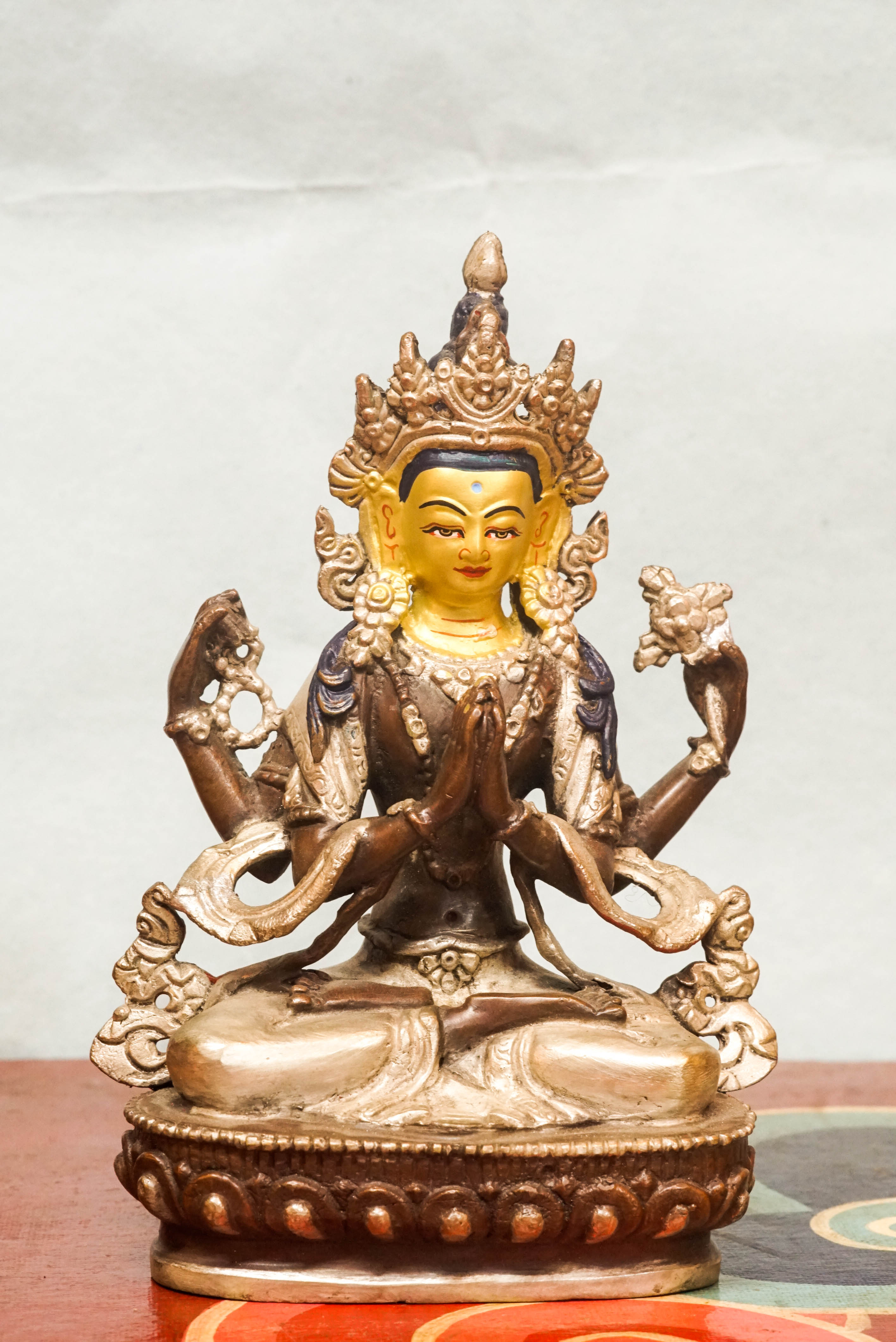 Chenrezig statue seated on a lotus base, holding a lotus flower and prayer beads, embodying compassion and spiritual guidance