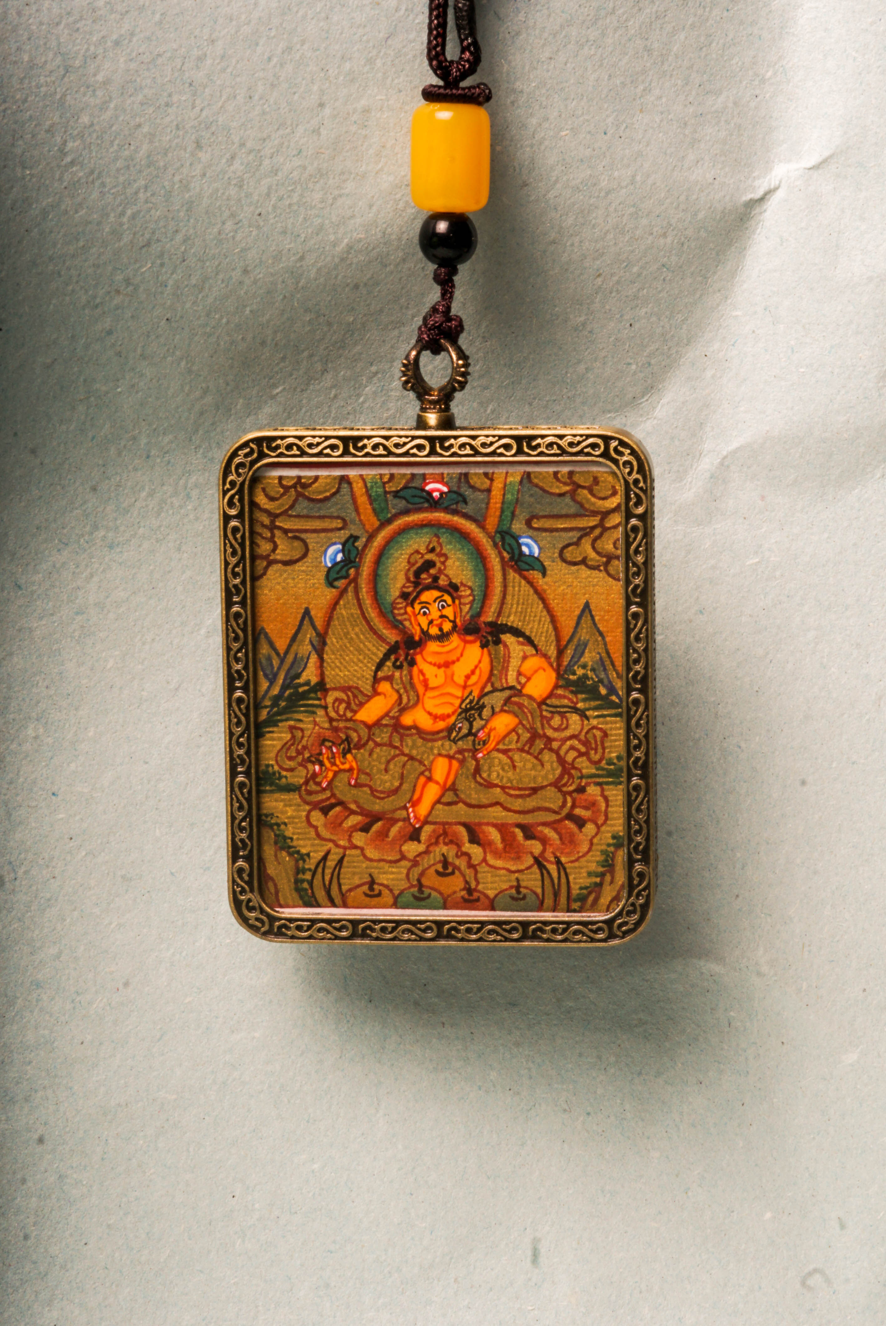 Zambala, the Tibetan Buddhist deity of wealth and prosperity, is revered for attracting abundance and removing obstacles. This Gold Zambala Thangka, hand-painted with mineral pigments and gold accents, embodies his blessings and brings spiritual harmony and success to your space.