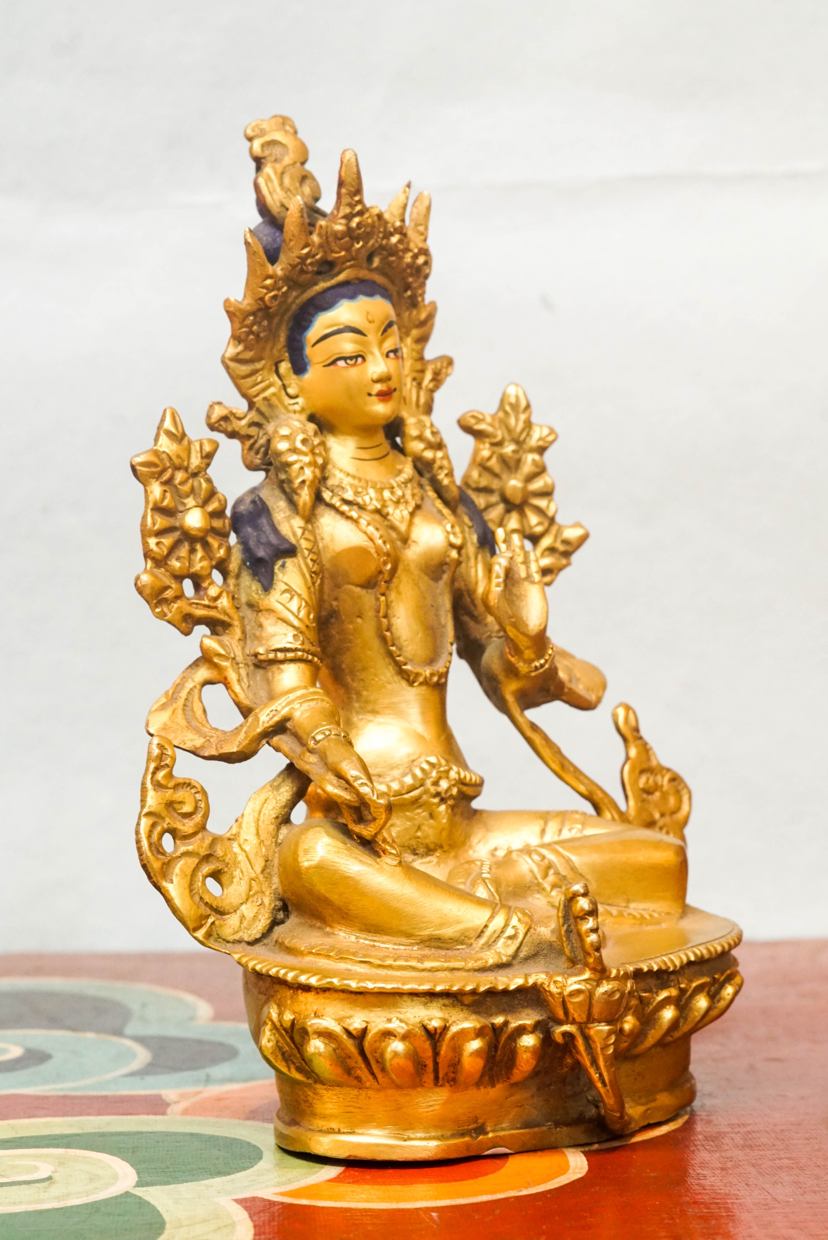 Green Tara statue seated on a lotus pedestal, with one leg extended and hands in protective and giving mudras, symbolizing her swift response to the suffering of sentient beings.