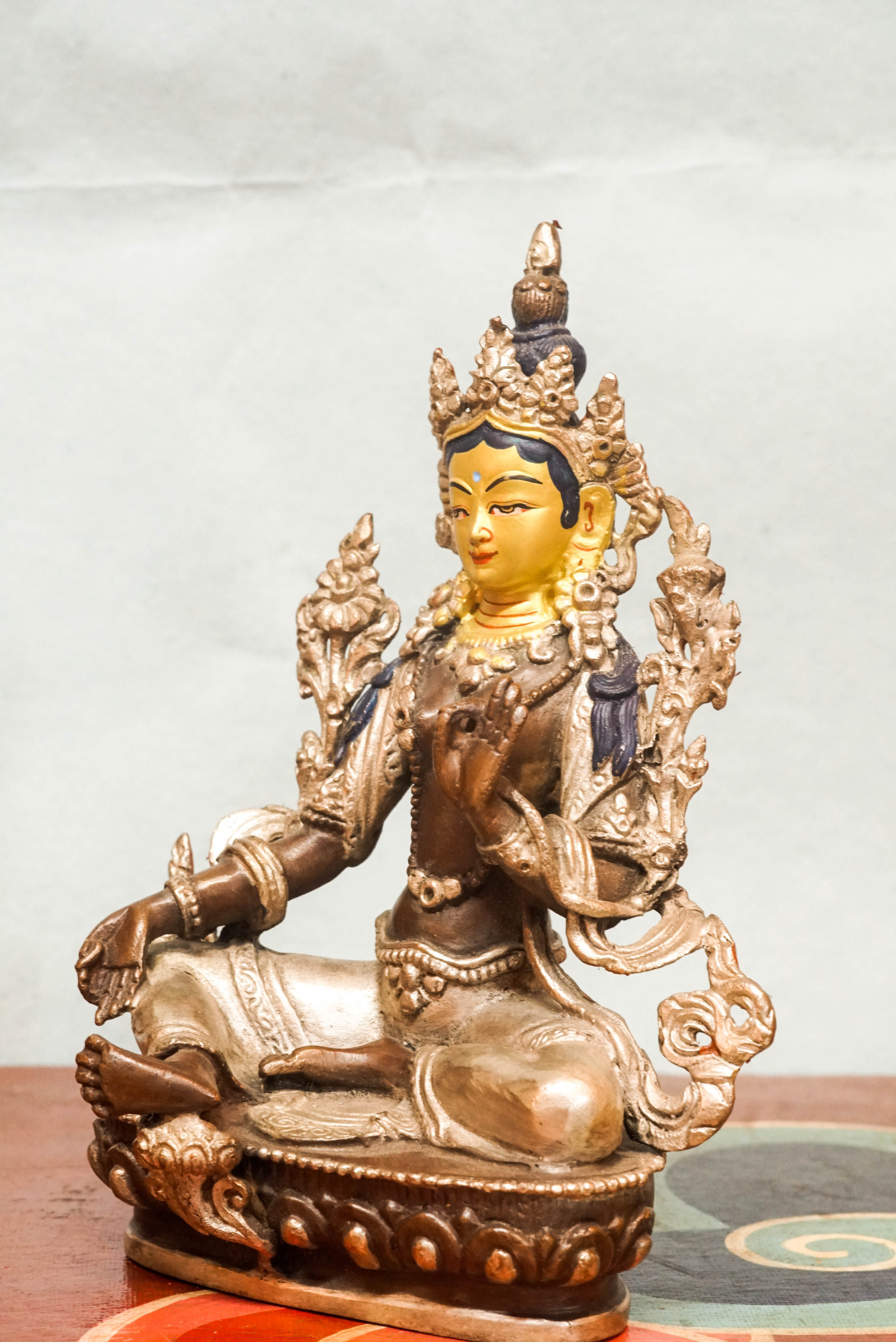 Statue of Green Tara, the female Bodhisattva of compassion and protection, seated with one leg extended, symbolizing her readiness to respond to suffering.