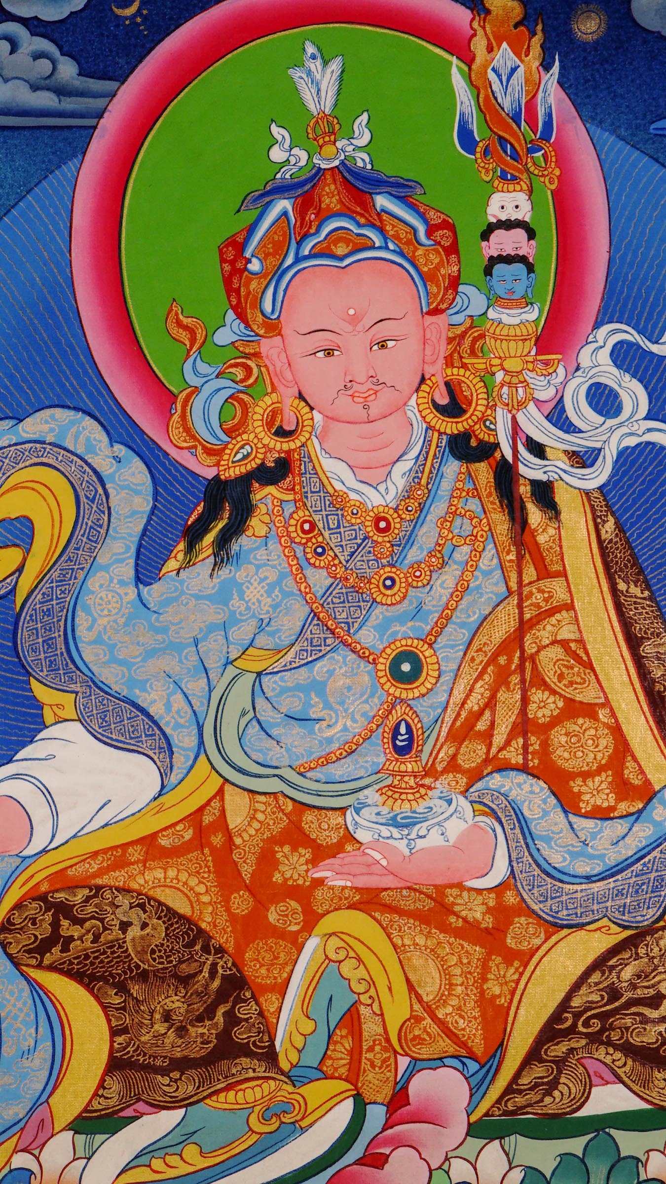 Hand-painted Guru Rinpoche thangka from Kathmandu, Nepal showing the master seated on a lotus throne holding a vajra, skull cup, and khatvanga staff with symbolic heads, adorned with robes, jewelry, and halo in traditional Tibetan Vajrayana style.