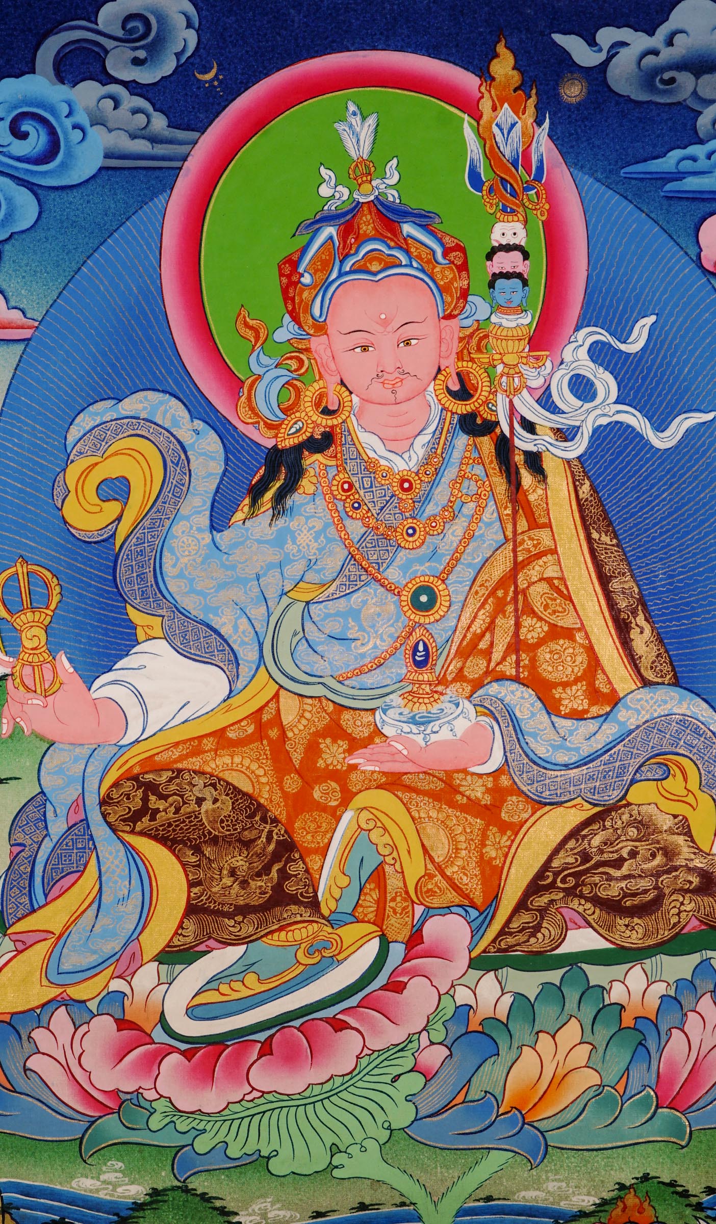 Hand-painted Guru Rinpoche thangka from Kathmandu, Nepal showing the master seated on a lotus throne holding a vajra, skull cup, and khatvanga staff with symbolic heads, adorned with robes, jewelry, and halo in traditional Tibetan Vajrayana style.