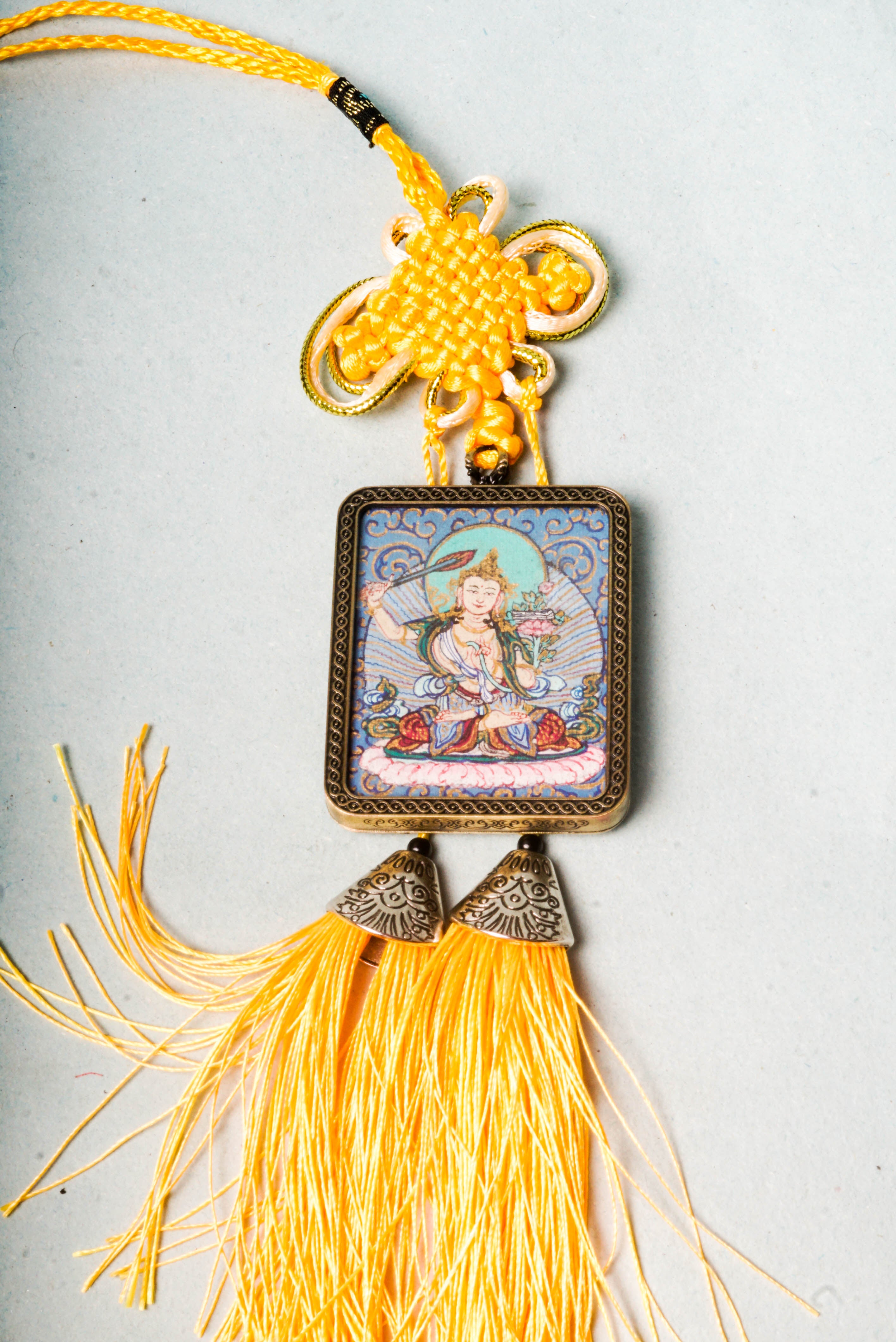 The Manjushri Ghau Thangka depicts the Bodhisattva of Wisdom, symbolizing clarity and insight. Hand-painted in a portable shrine format, it features his iconic sword and scripture, aiding in meditation and the pursuit of spiritual knowledge.