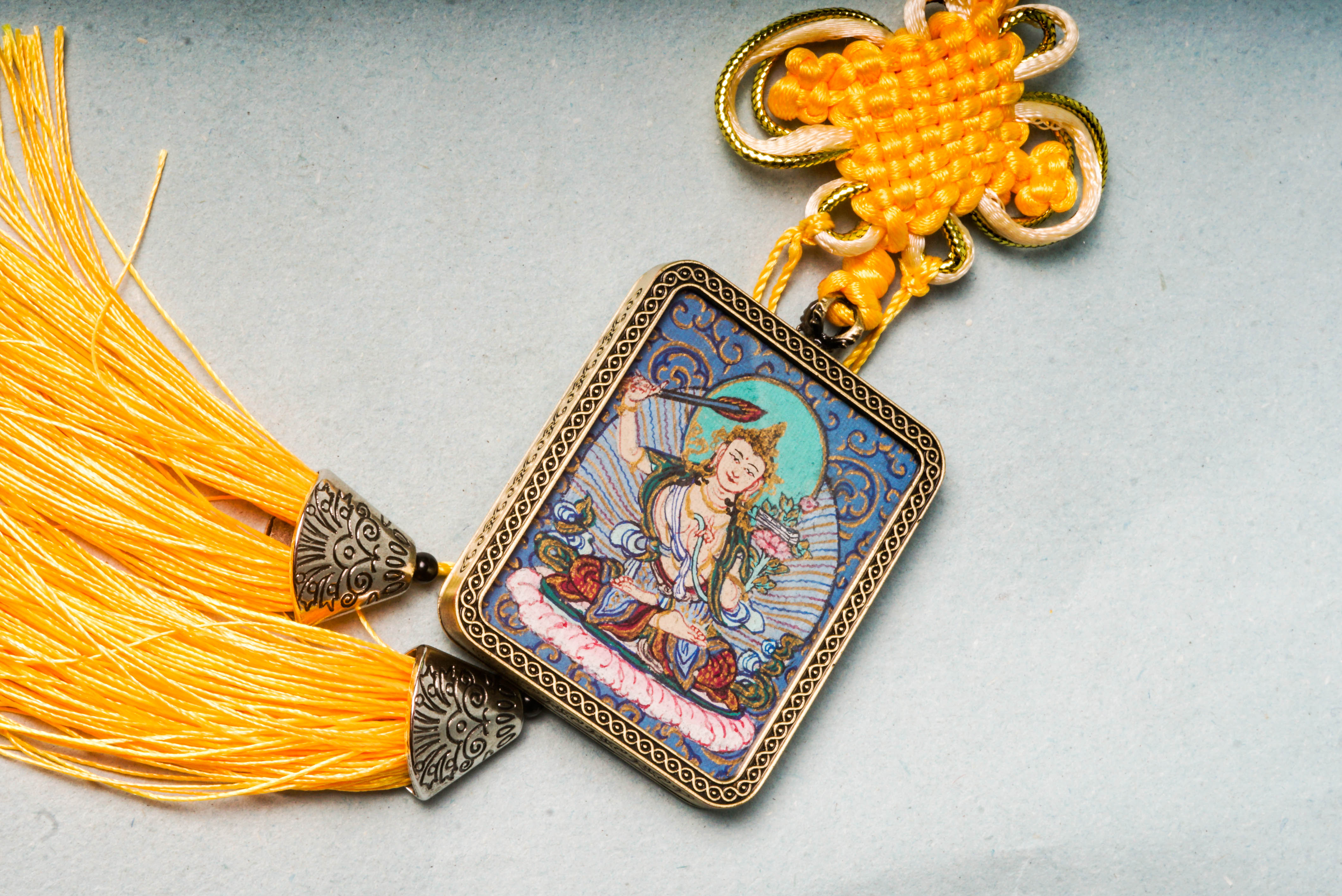 The Manjushri Ghau Thangka depicts the Bodhisattva of Wisdom, symbolizing clarity and insight. Hand-painted in a portable shrine format, it features his iconic sword and scripture, aiding in meditation and the pursuit of spiritual knowledge.
