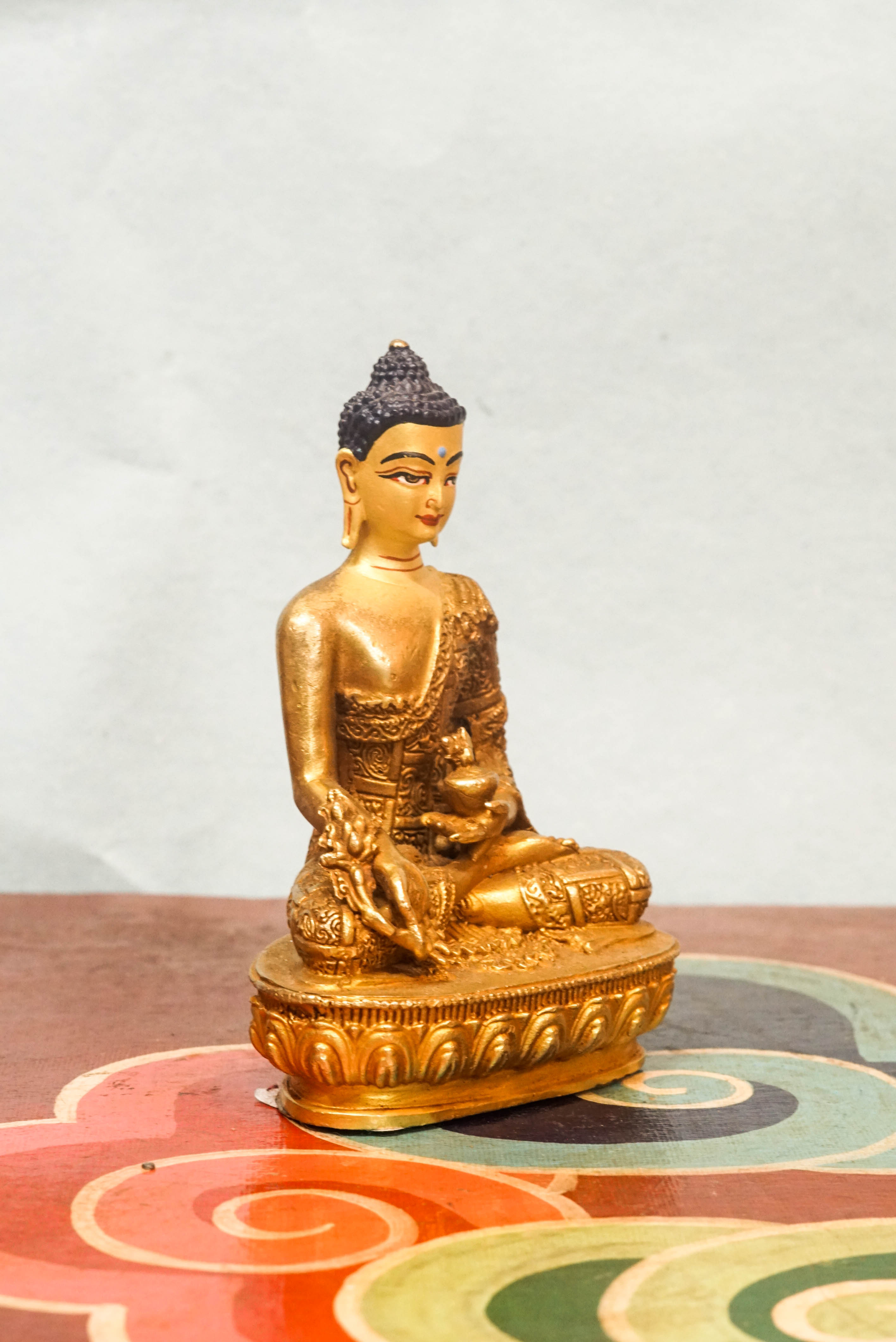 Handcrafted Medicine Buddha statue with fully opened eyes, holding a healing bowl, surrounded by a radiant lapis aura, seated on a lotus pedestal.