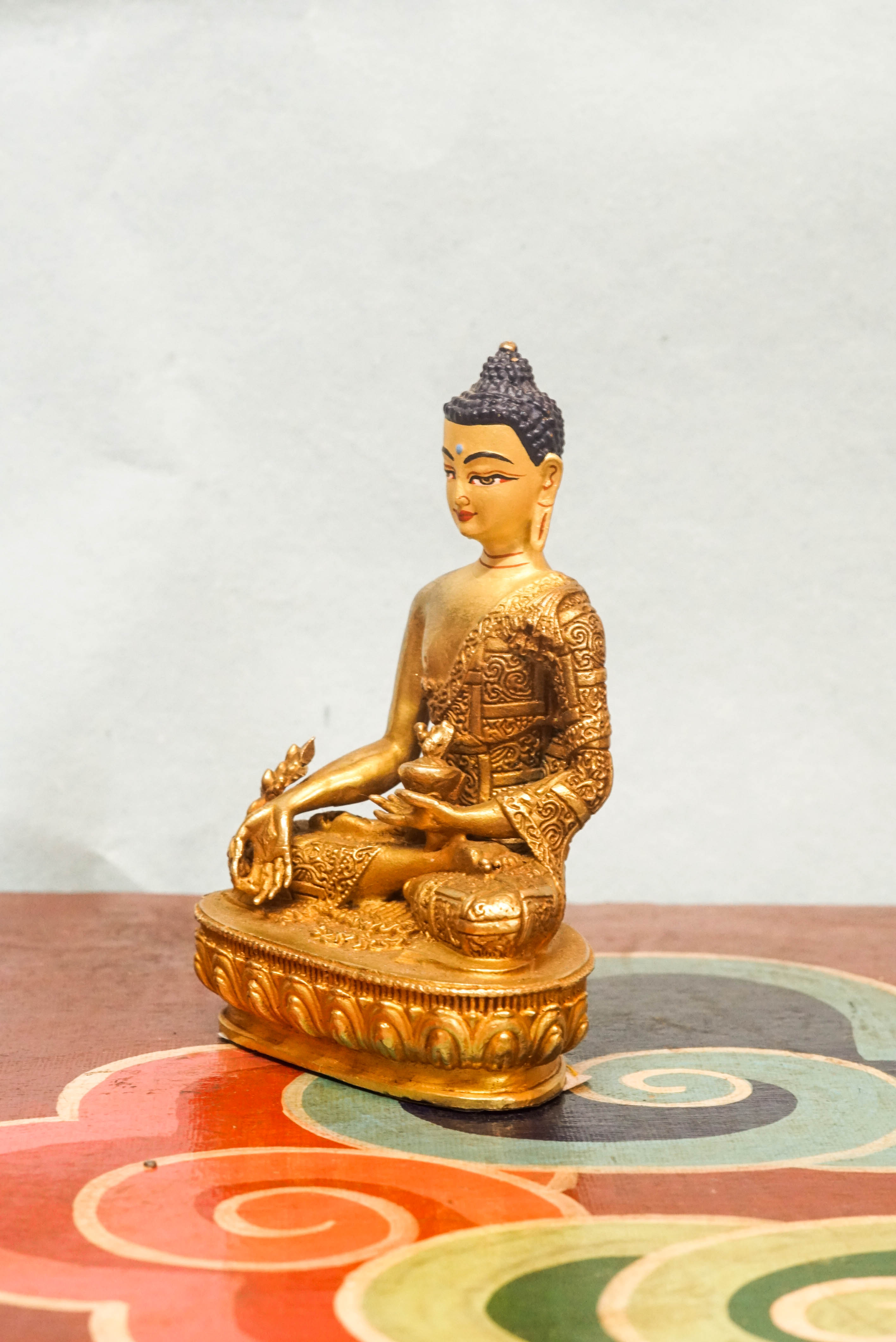 Handcrafted Medicine Buddha statue with fully opened eyes, holding a healing bowl, surrounded by a radiant lapis aura, seated on a lotus pedestal.