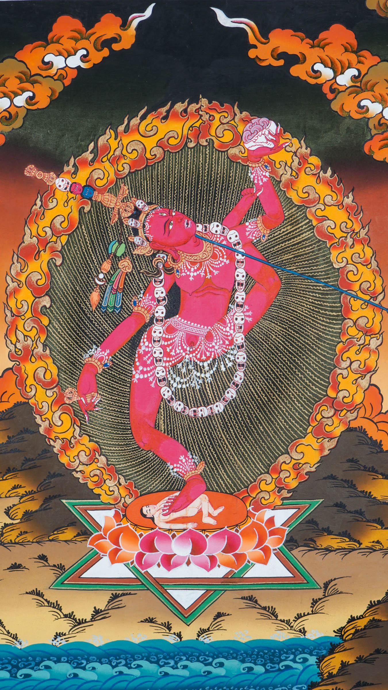 Traditional Tibetan thangka painting depicting Vajrayogini in a dynamic dancing pose on a lotus throne, encircled by flames and clouds, holding ritual implements against a warm, mountainous landscape.