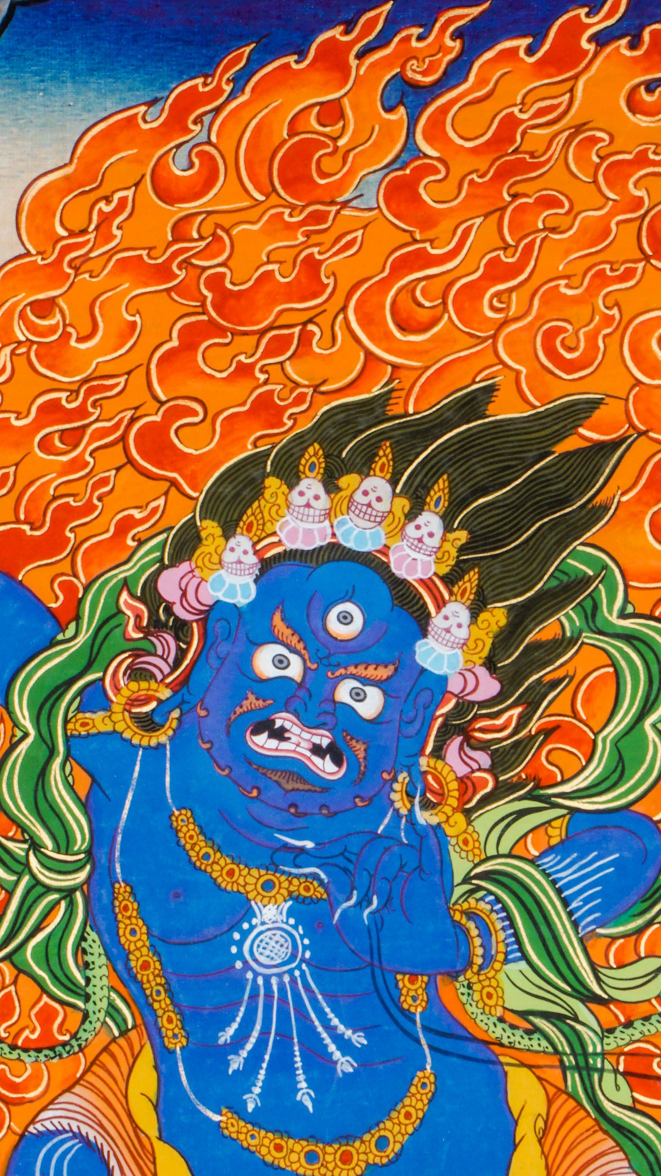 Traditional Tibetan thangka painting depicting Vajrapani, a blue-skinned wrathful deity in a powerful stance on a lotus throne, encircled by flames, with clouds and mountains in the background.