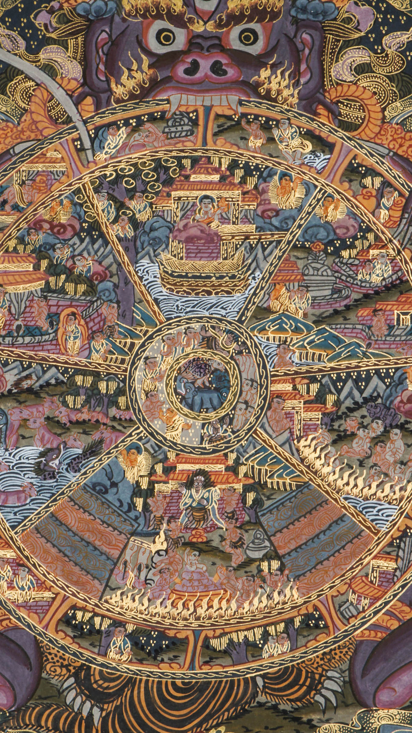 Detailed thangka-style painting showing a large circular wheel divided into multiple sections filled with small human figures, animals, buildings, and landscape scenes, surrounded by concentric decorative rings and held by a large blue multi-eyed figure with extended arms, set against a dark background with clouds, flames, and ornate gold, red, and blue patterns.