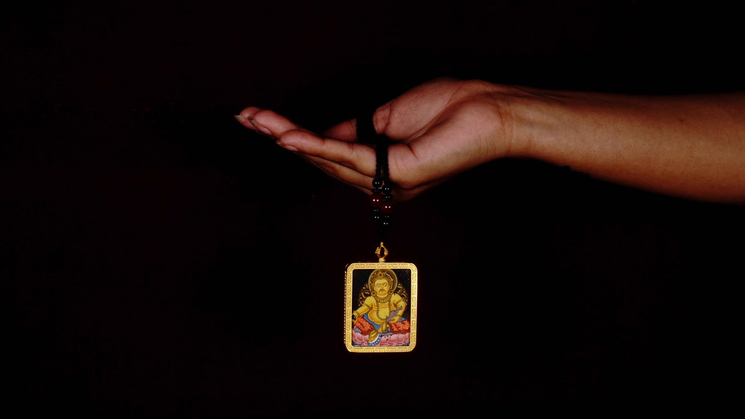 Hand-painted Yellow Zambala miniature Thangka pendant in gold-accented copper Ghau locket with black beaded cord.