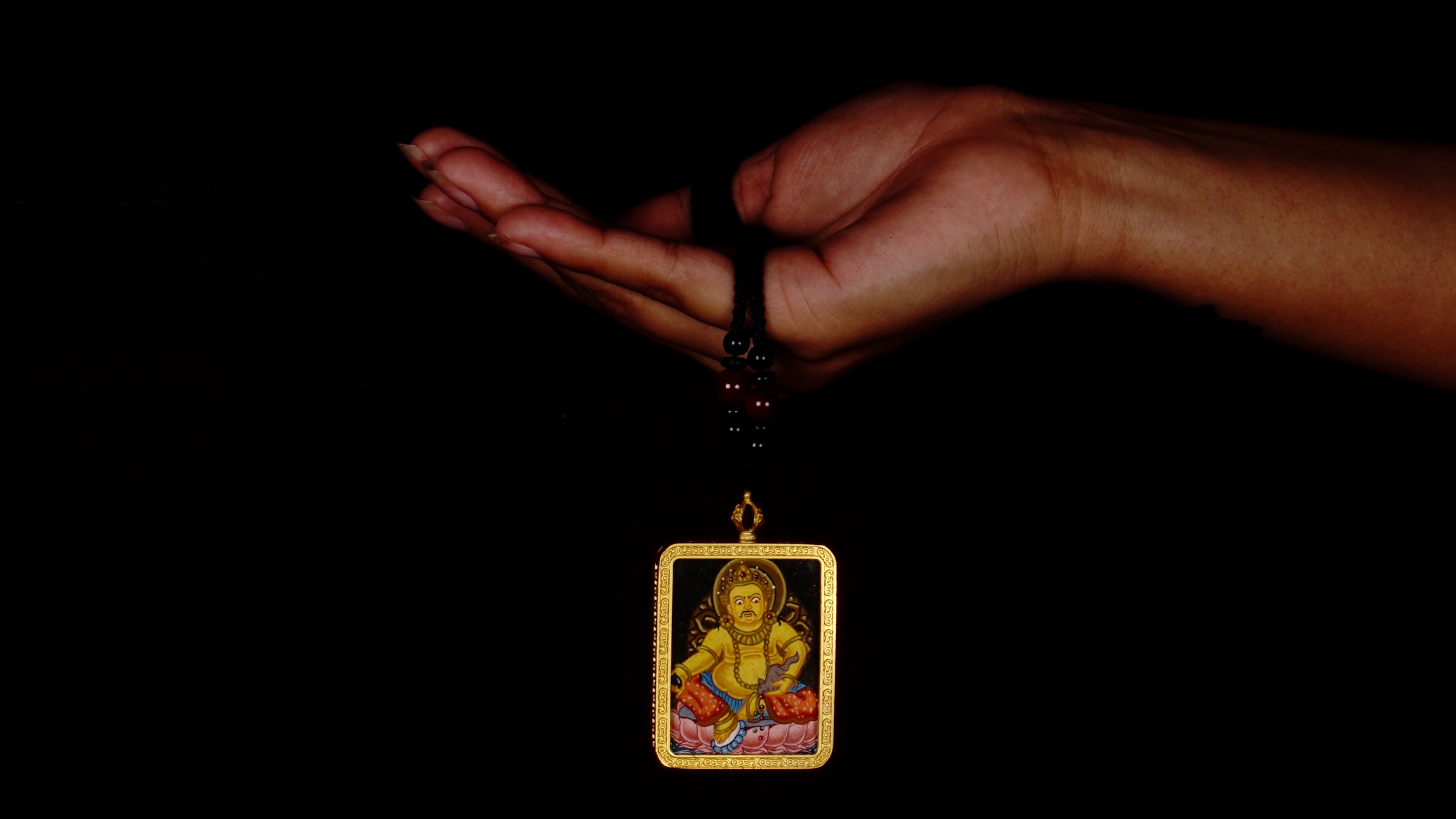 Hand-painted Yellow Zambala miniature Thangka pendant in gold-accented copper Ghau locket with black beaded cord.