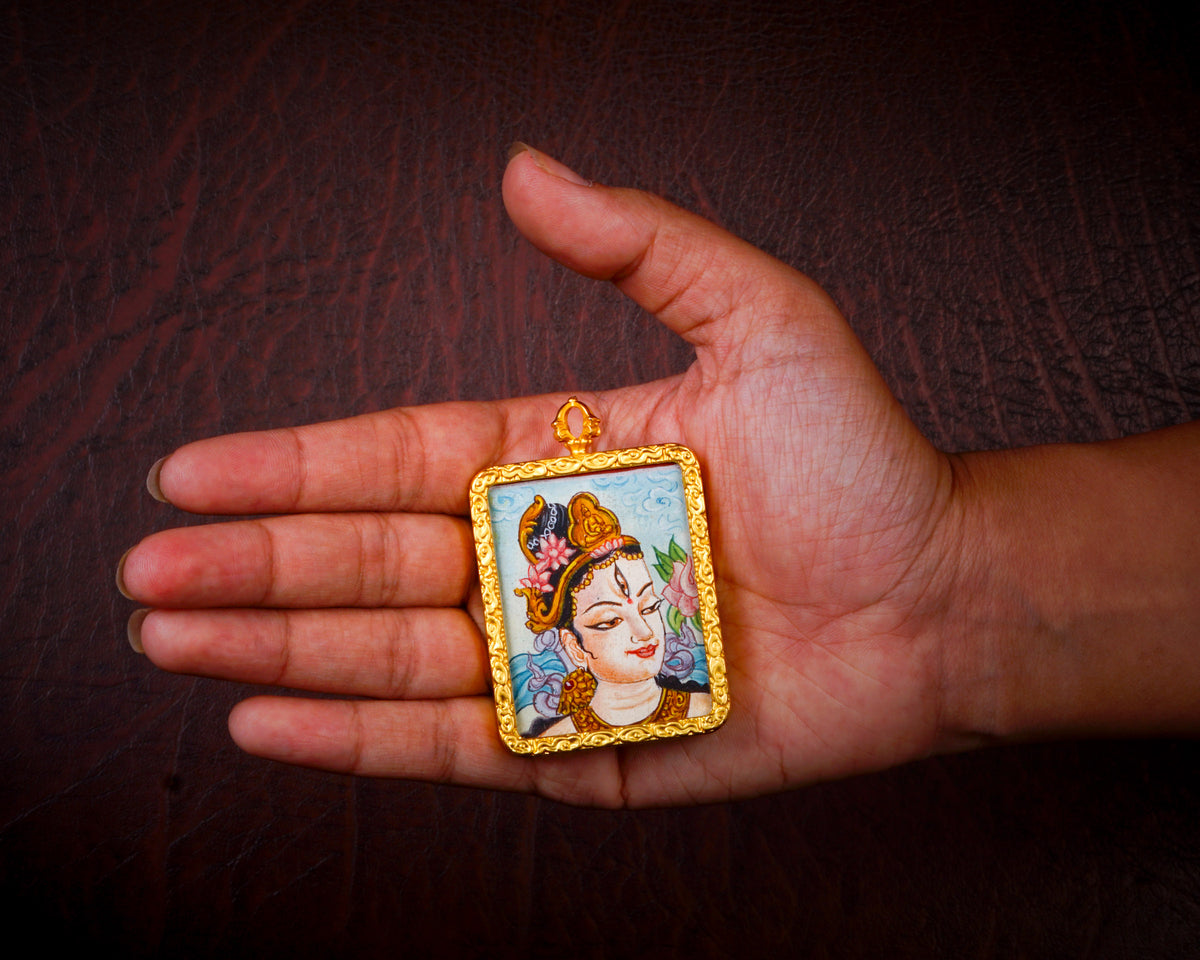 White Tara Ghau pendant featuring a miniature Tibetan Buddhist goddess of compassion artwork in a decorative gold-tone frame handcrafted in Nepal.