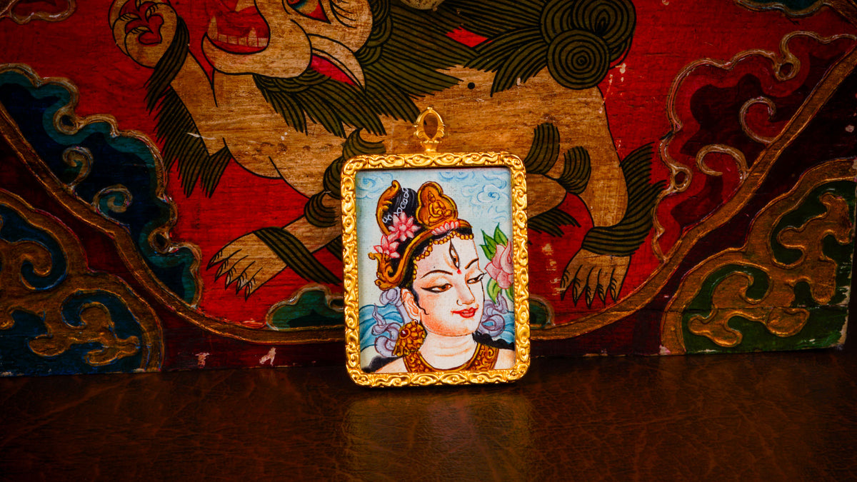 White Tara Ghau pendant featuring a miniature Tibetan Buddhist goddess of compassion artwork in a decorative gold-tone frame handcrafted in Nepal.