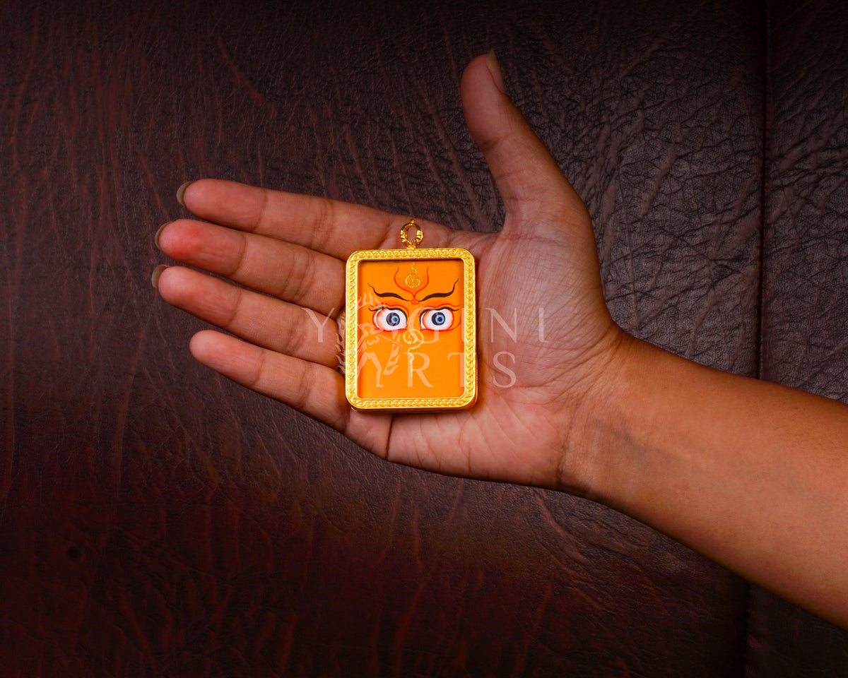 Hand-painted Zambhala Eyes Ghau pendant with sacred Buddha Wisdom Eyes in a handcrafted gold-tone frame made in Nepal.