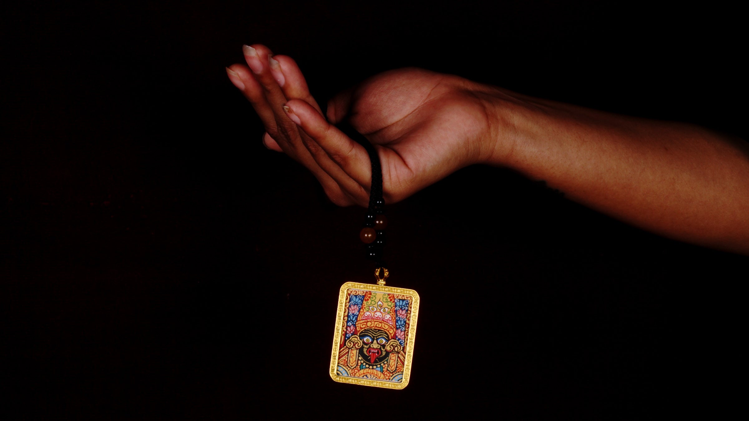 Hand-painted Goddess Kali miniature Thangka pendant in gold-accented copper Ghau locket with black beaded cord.