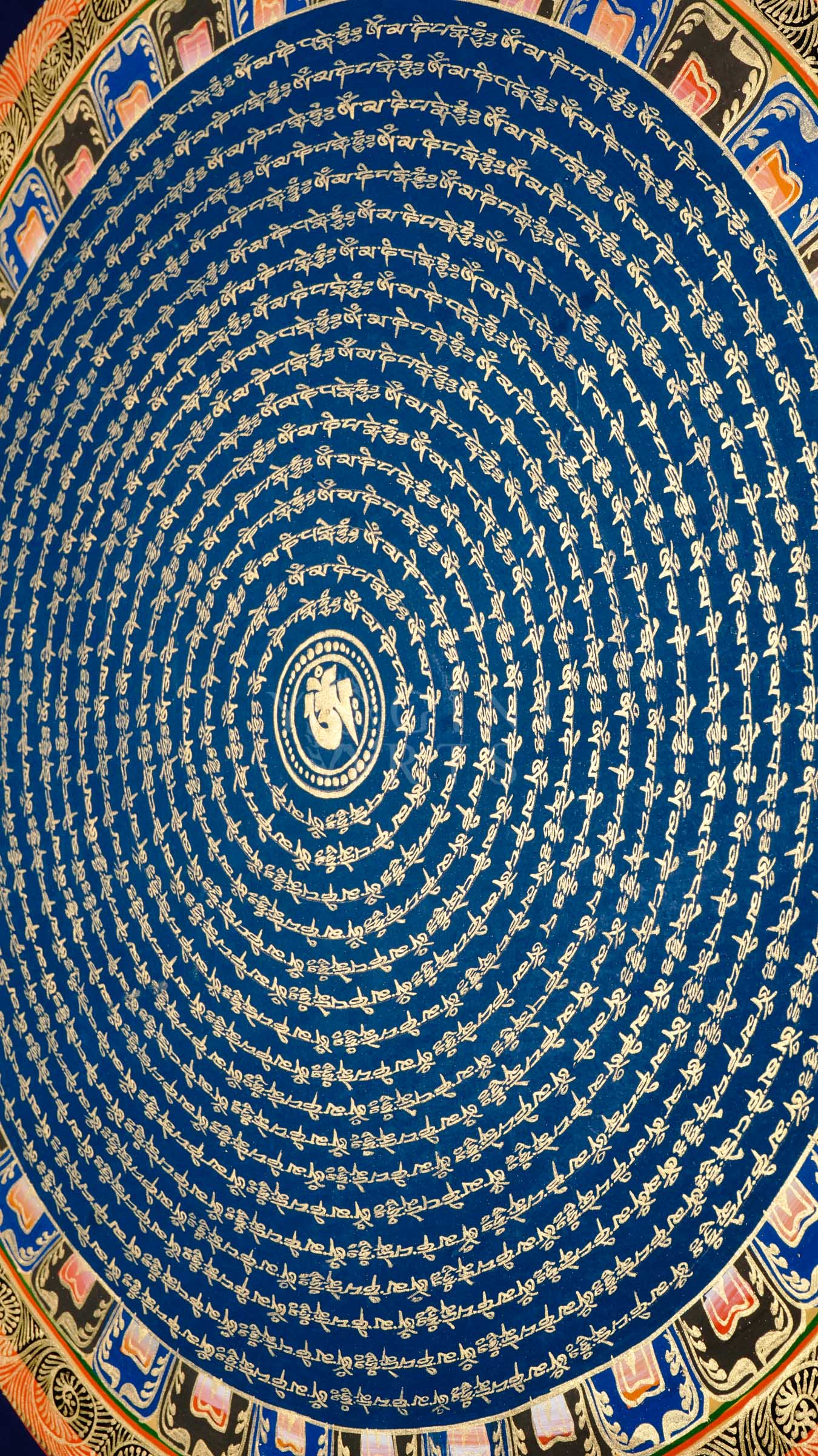 Blue Om Mantra Mandala thangka featuring sacred Om symbol surrounded by concentric circles of gold Tibetan mantra calligraphy and floral corner motifs.