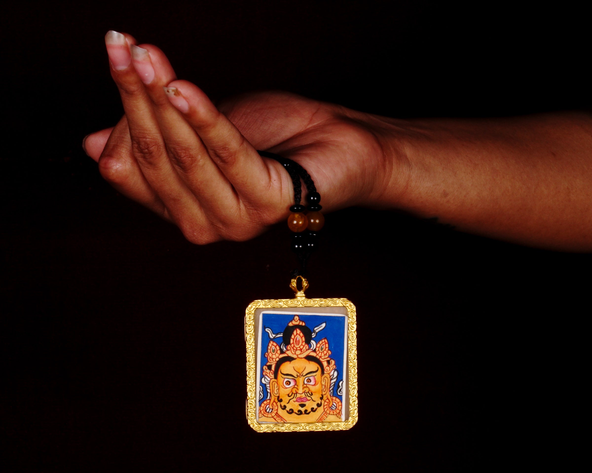 Hand-painted Zambala wealth deity miniature Thangka pendant in gold-accented copper Ghau locket with black beaded cord.