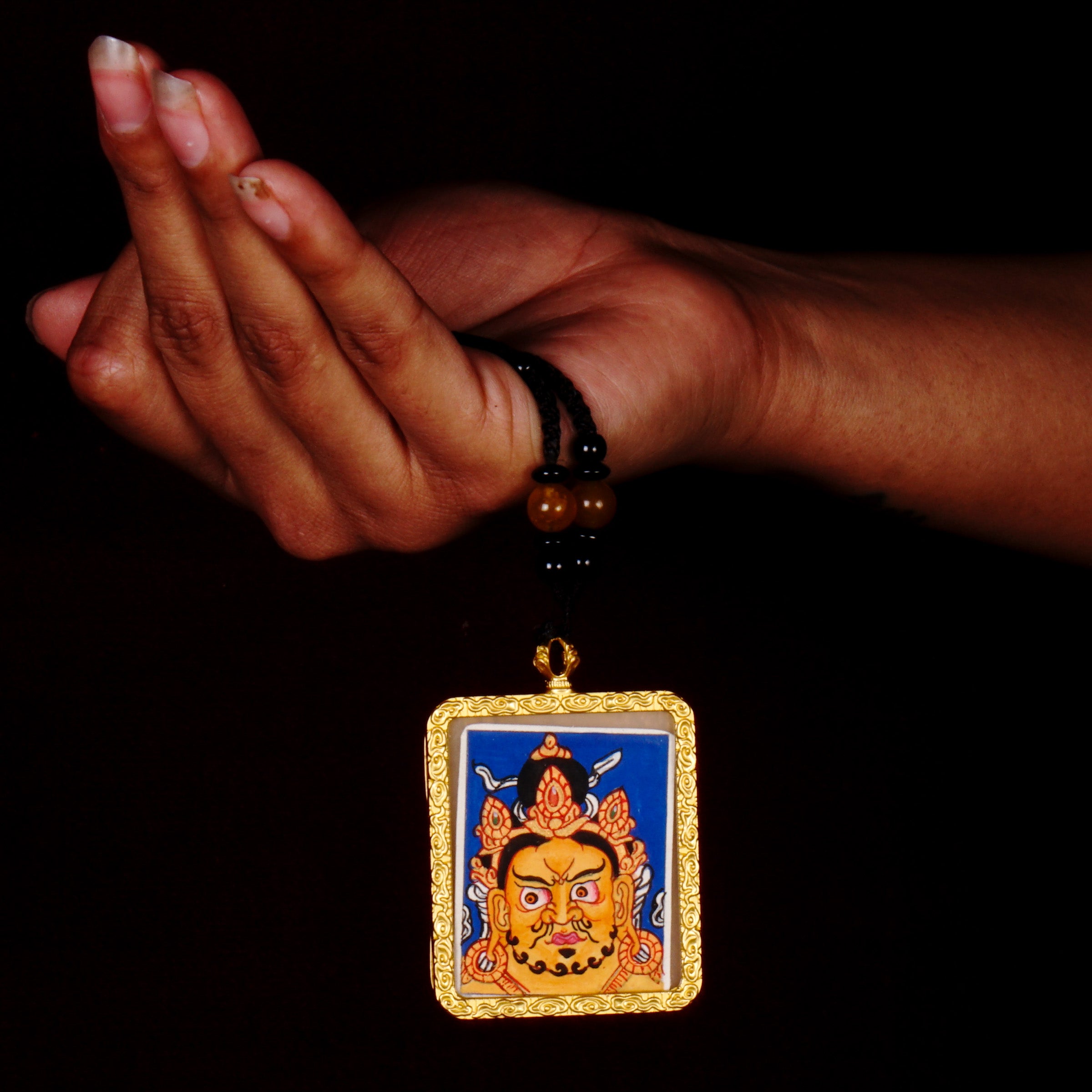 Hand-painted Zambala wealth deity miniature Thangka pendant in gold-accented copper Ghau locket with black beaded cord.