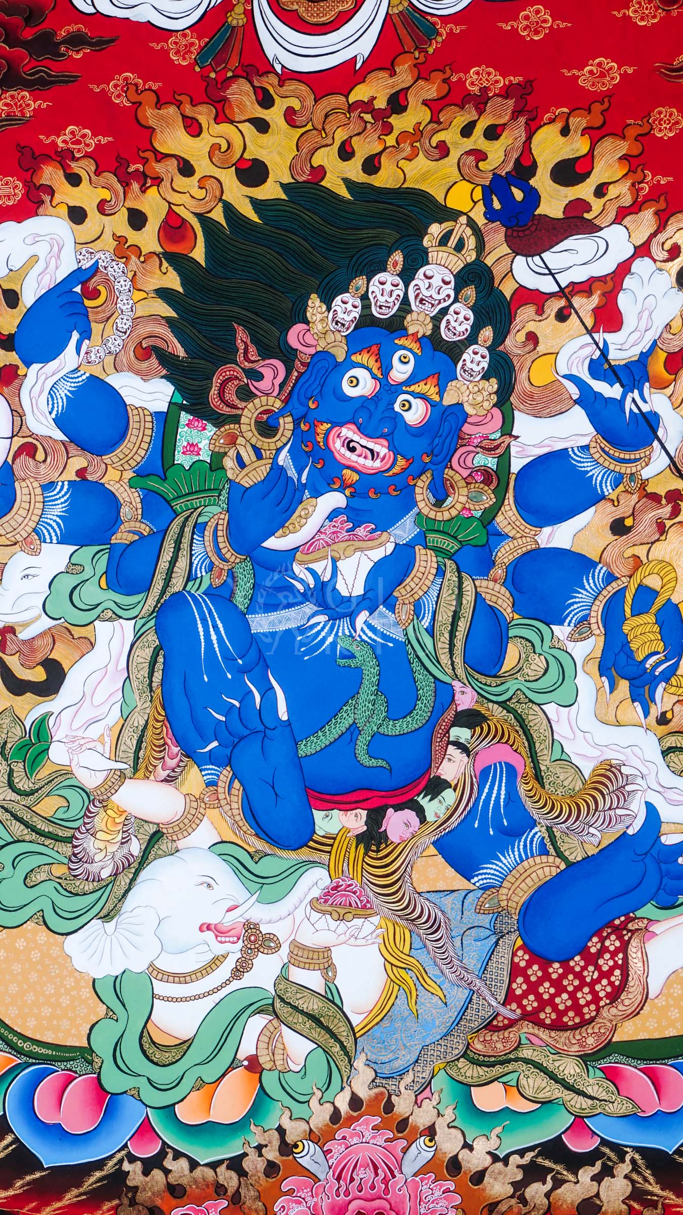 Hand-painted Tibetan thangka of Six-Armed Mahakala surrounded by blazing wisdom flames, holding sacred tantric implements against a vivid red Himalayan background.