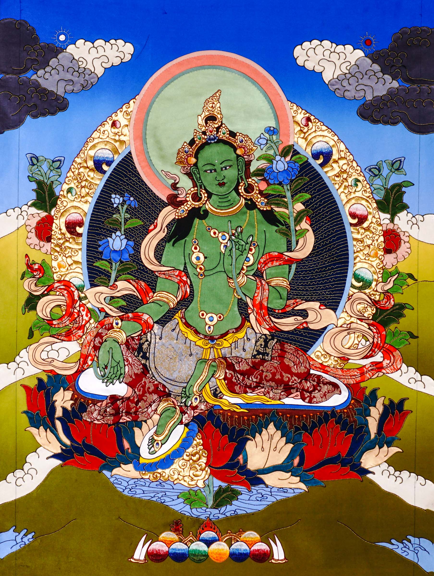 Green Tara cloth thangka printed on fabric showing Tibetan Buddhist goddess seated on lotus holding blue utpala lotus with vibrant halo background.