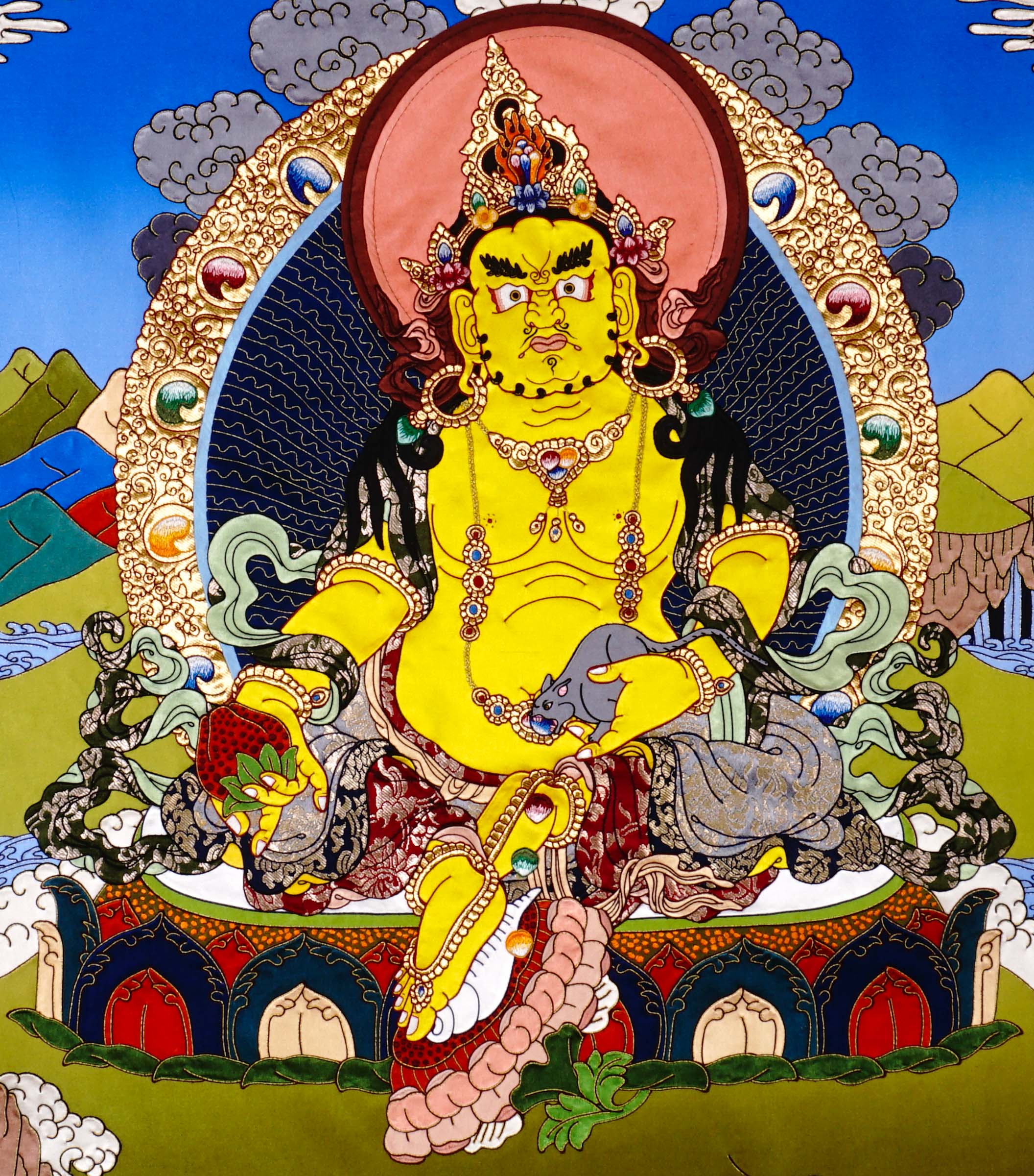 Yellow Dzambhala cloth thangka printed on fabric showing Tibetan wealth deity seated on lotus throne holding mongoose and citron with vibrant landscape background.