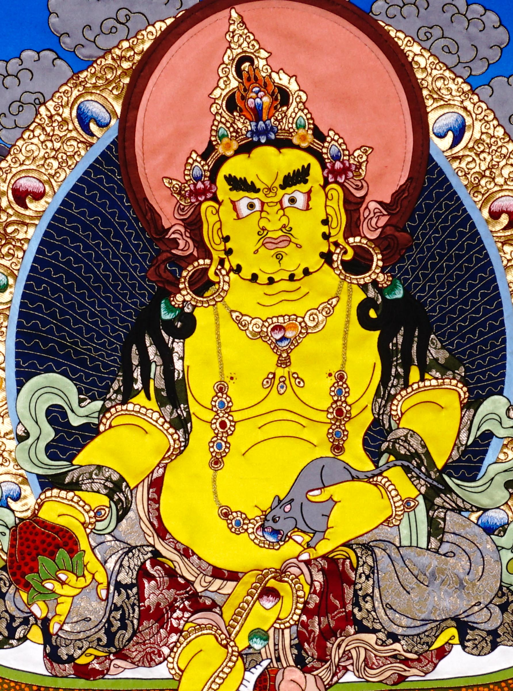 Yellow Dzambhala cloth thangka printed on fabric showing Tibetan wealth deity seated on lotus throne holding mongoose and citron with vibrant landscape background.