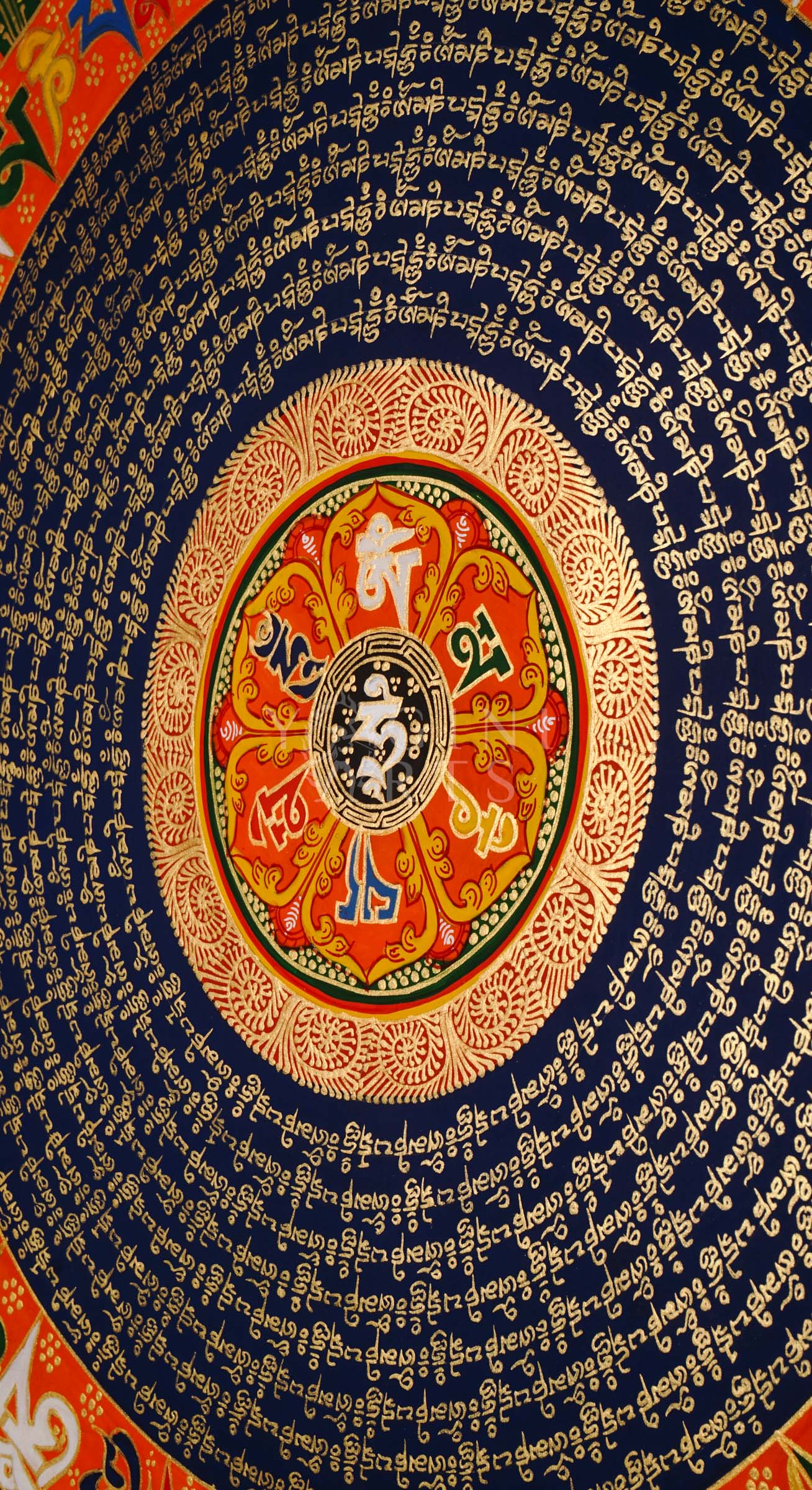 Tibetan mantra mandala thangka with blue background, gold script rings, colorful outer mantra band, and floral corner decorations.