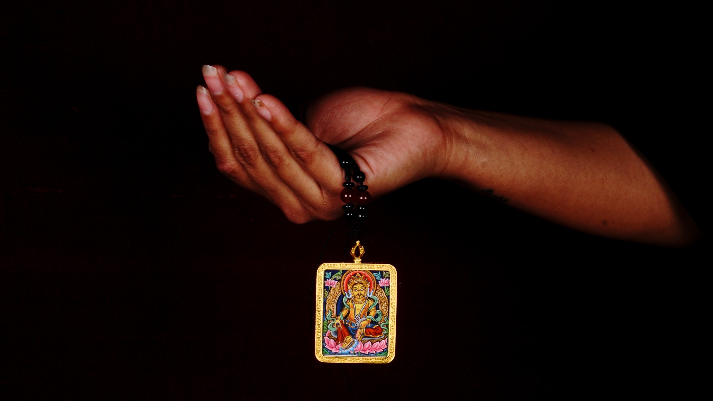 Hand-painted Yellow Zambala miniature Thangka pendant in gold-accented copper Ghau locket with black beaded cord.