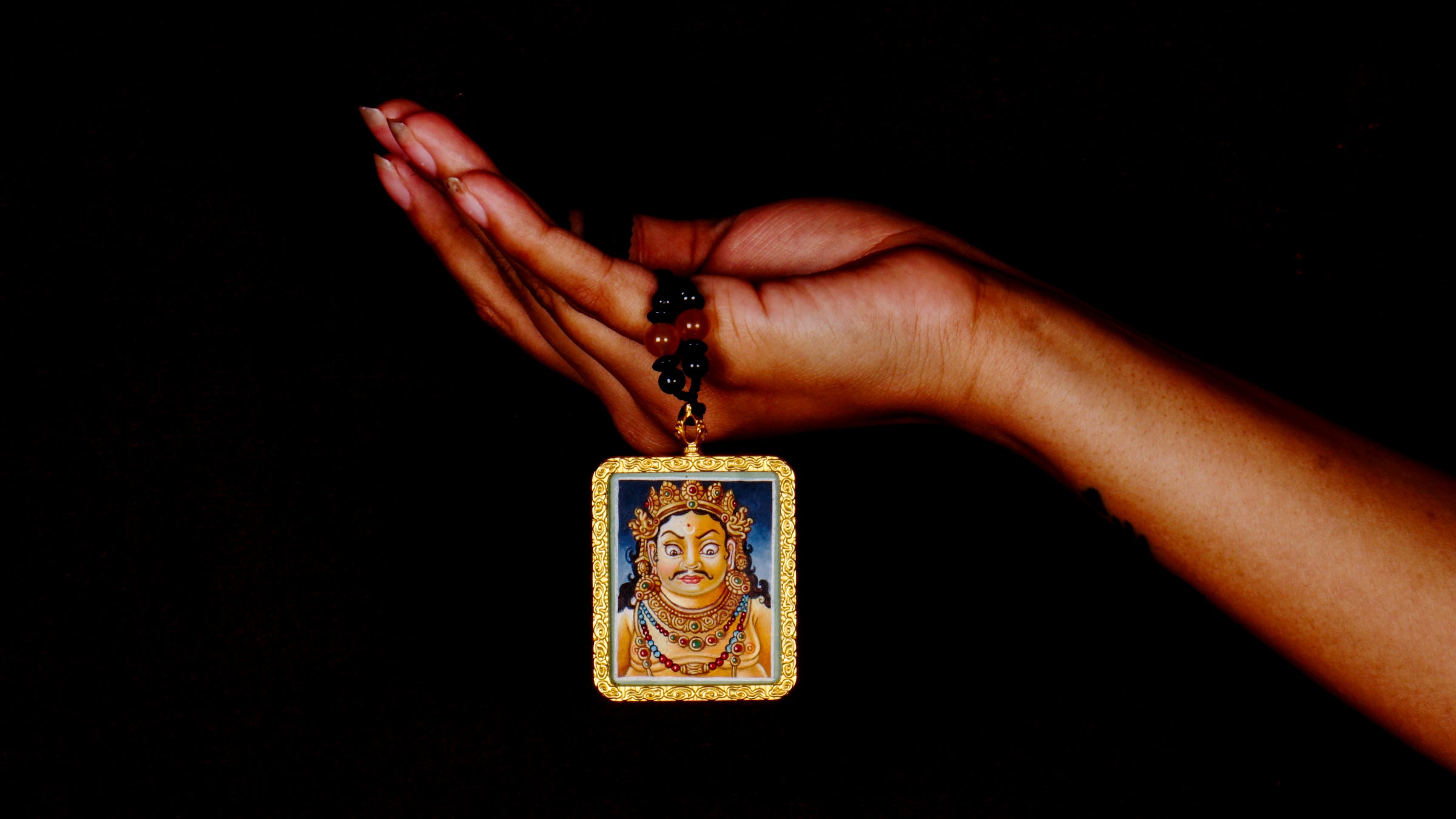 Hand-painted Zambala portrait miniature Thangka pendant in gold-accented copper Ghau locket with black beaded cord.