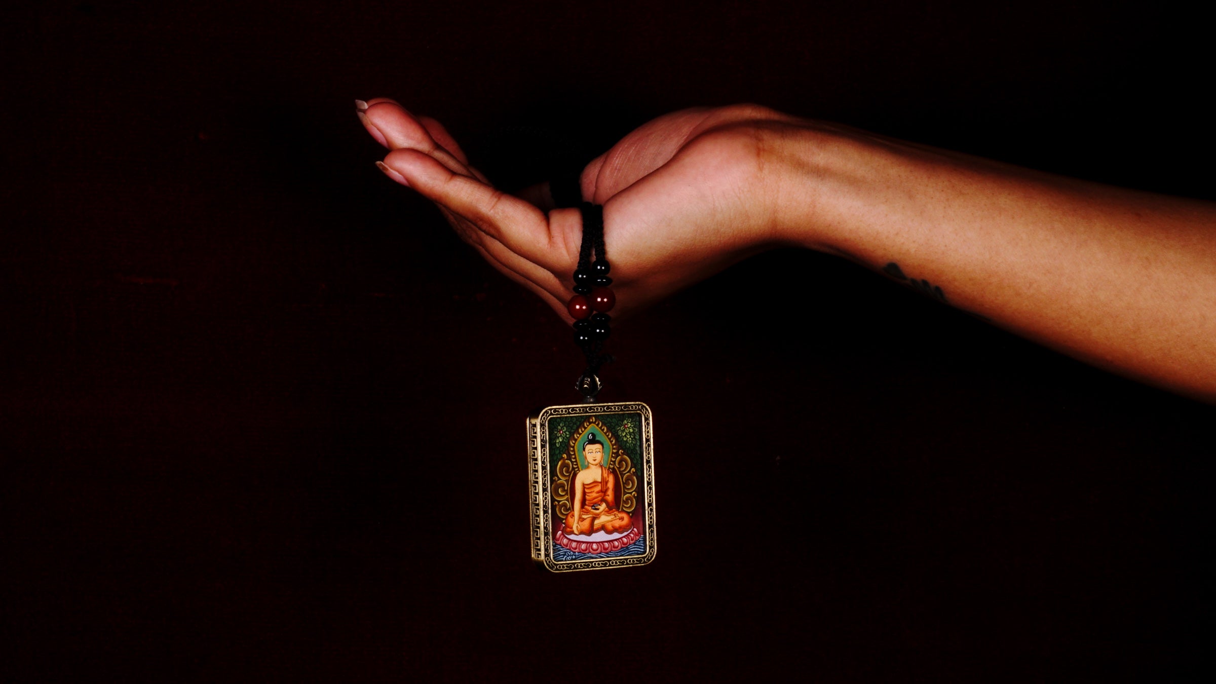 Hand-painted Shakyamuni Buddha miniature Thangka pendant in gold-accented copper Ghau locket with black beaded cord.