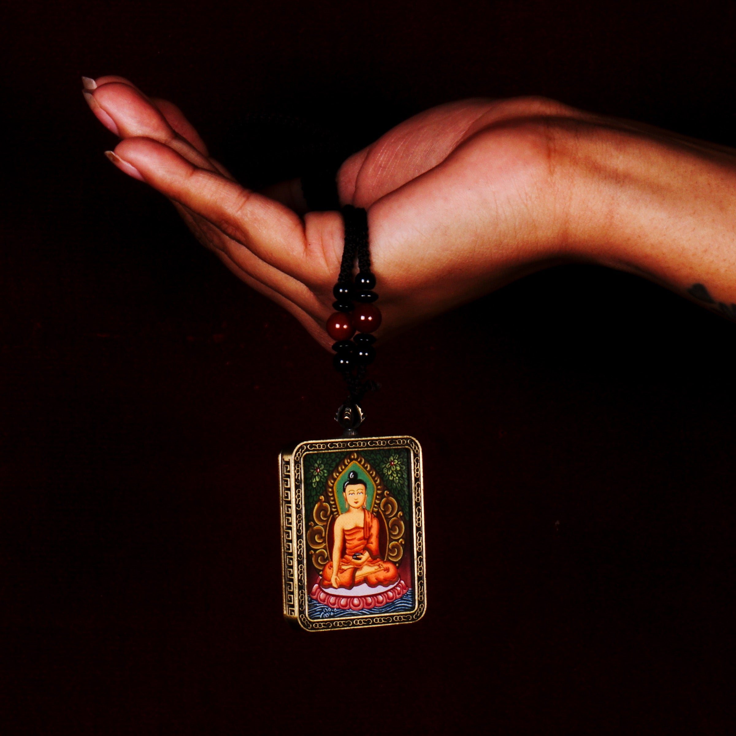 Hand-painted Shakyamuni Buddha miniature Thangka pendant in gold-accented copper Ghau locket with black beaded cord.