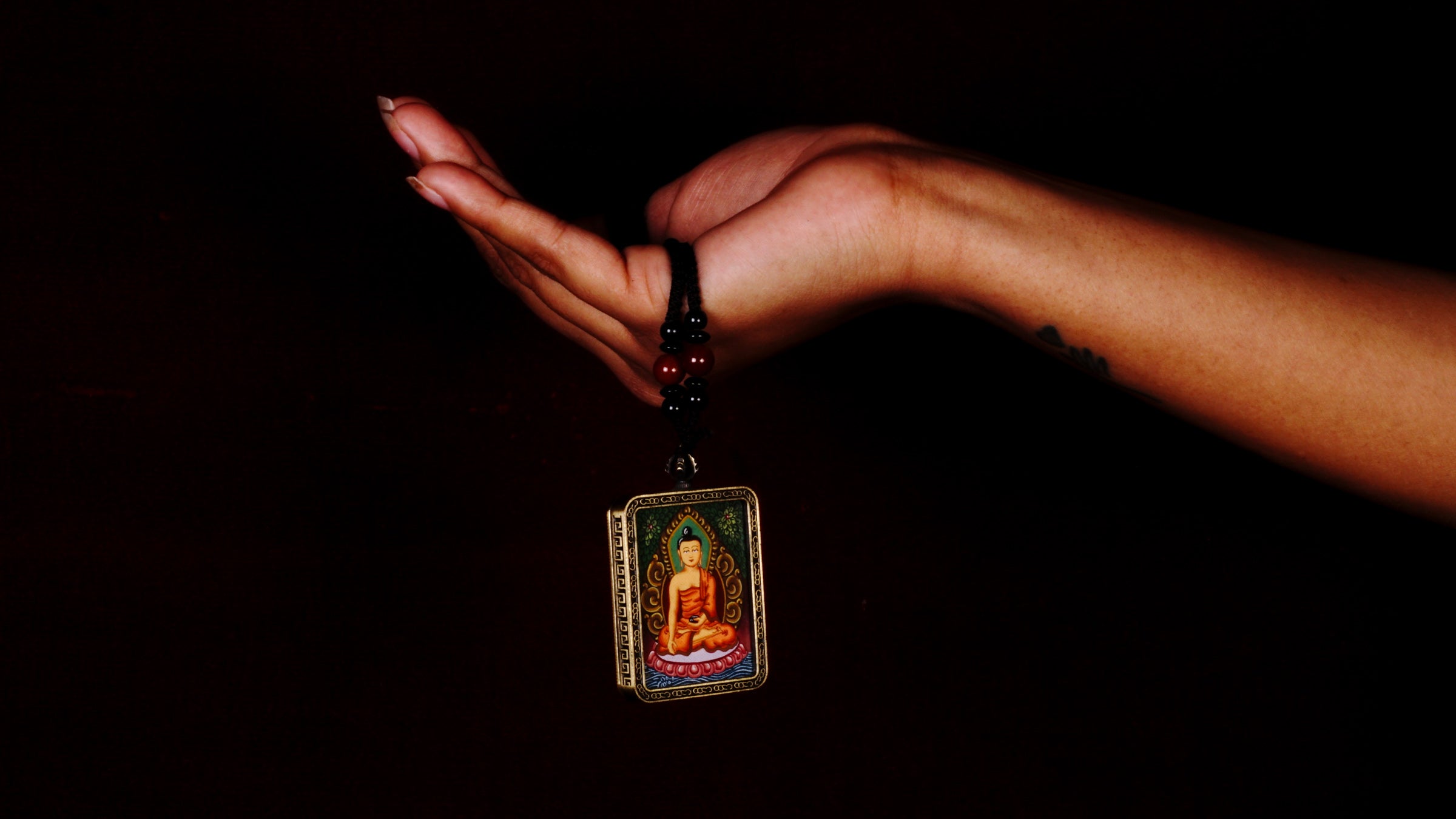 Hand-painted Shakyamuni Buddha miniature Thangka pendant in gold-accented copper Ghau locket with black beaded cord.
