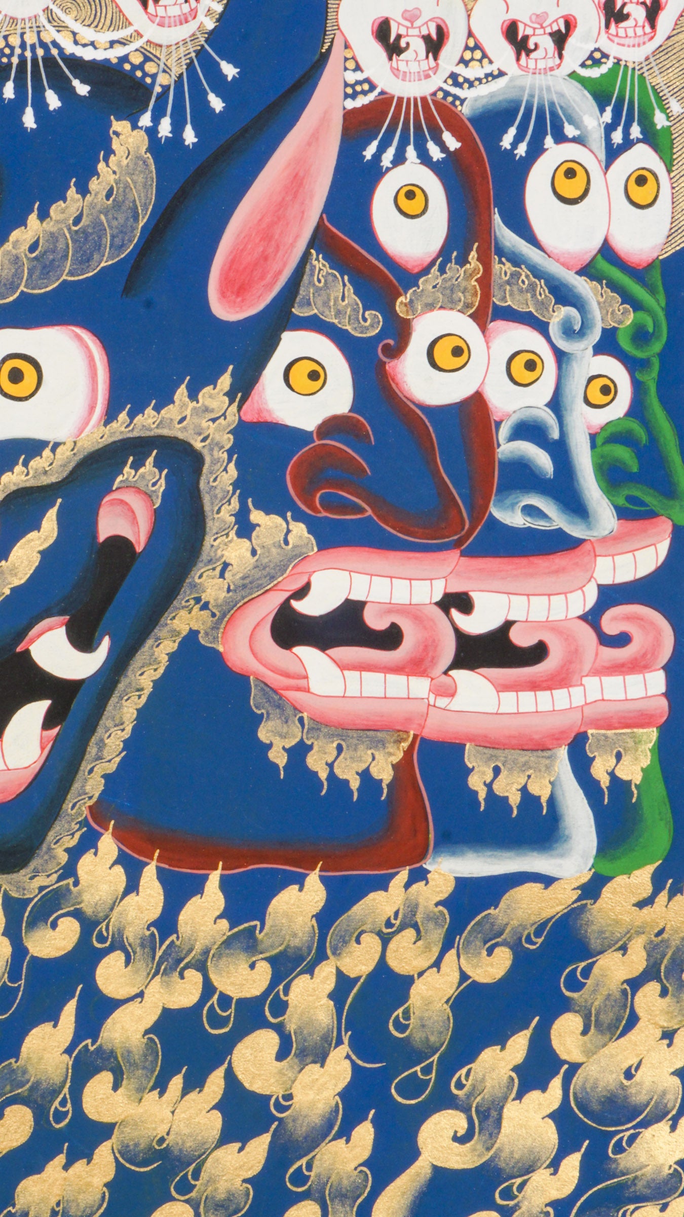 Thangka painting showing a large blue multi-faced figure with numerous eyes and open mouths, crowned by smaller faces and skull motifs, set against a gold halo and stylized cloud background.