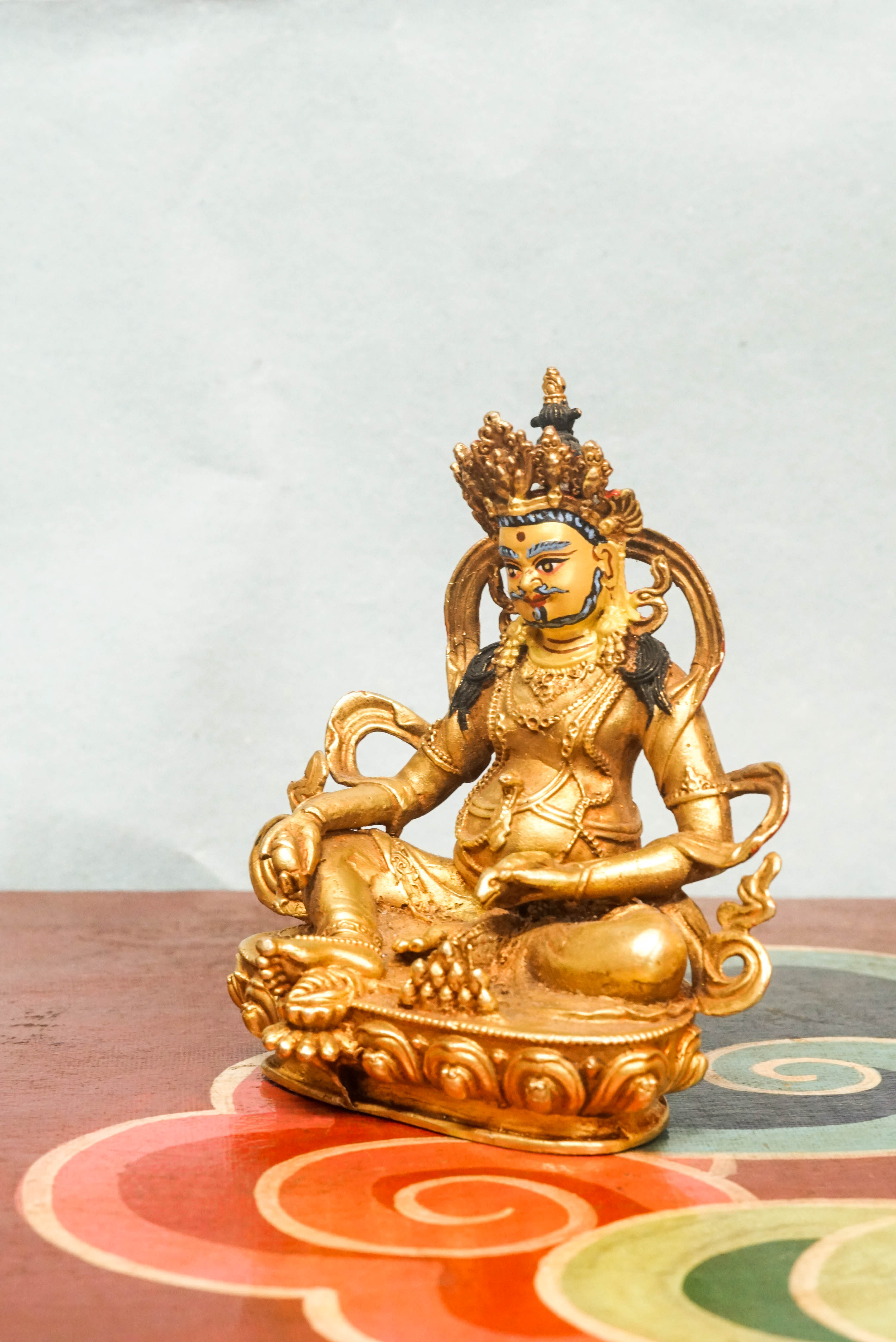 Handmade gold Zambala statue adorned with crown and jewelry, symbolizing prosperity and removal of obstacles.