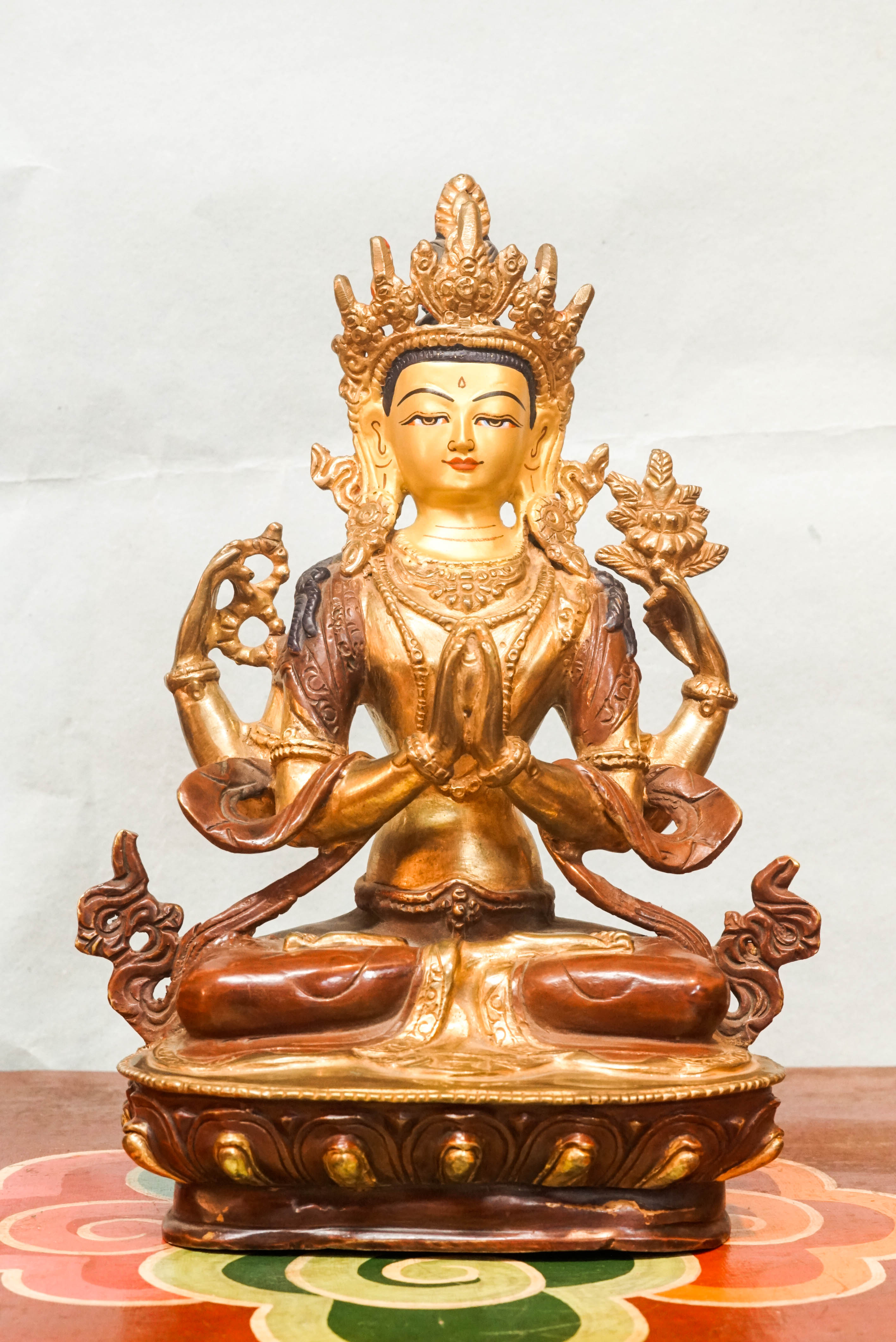 Intricately carved Avalokiteshvara (Chenrezig) statue seated on a lotus pedestal, with multiple arms representing boundless compassion and the ability to assist countless beings simultaneously.