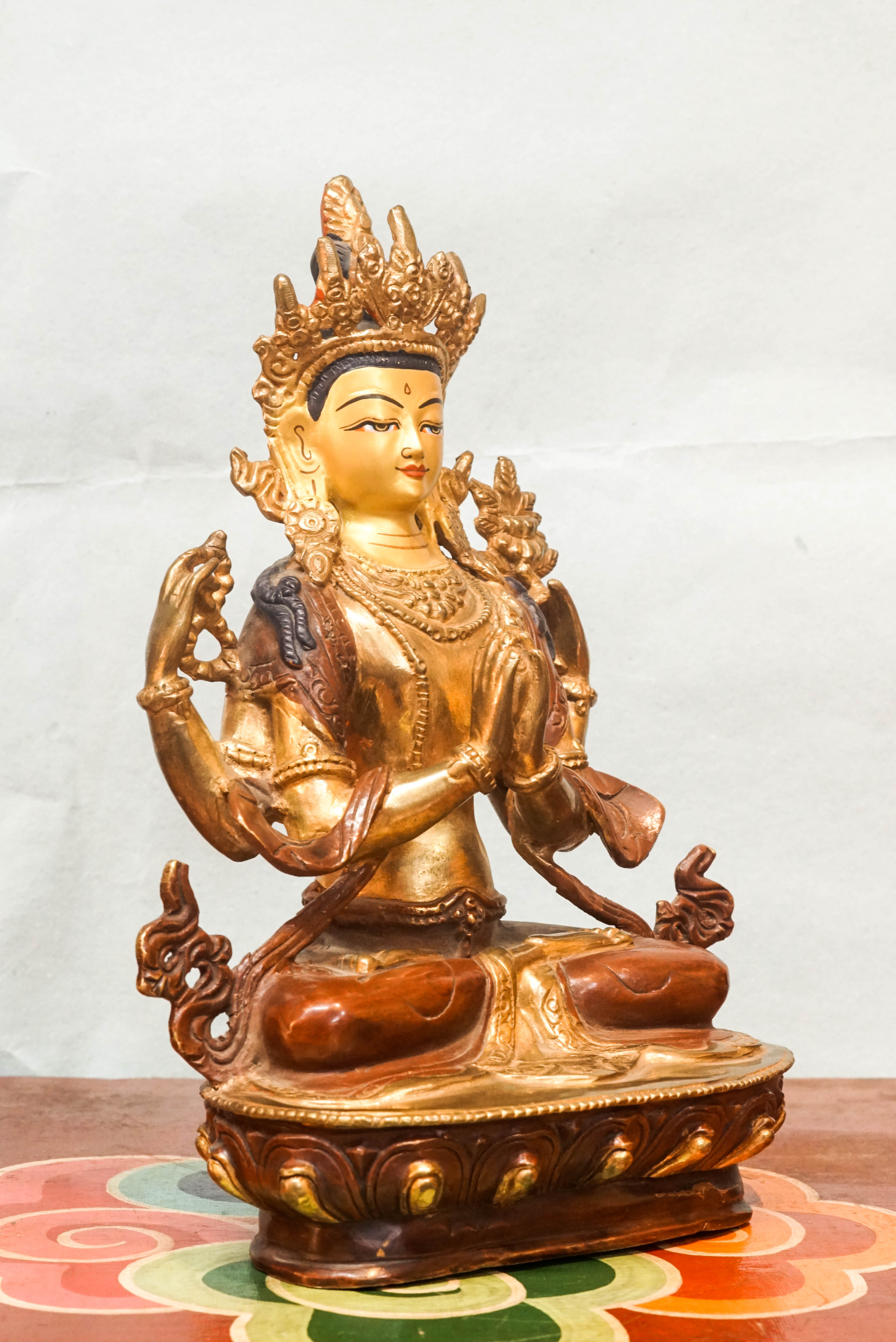 Intricately carved Avalokiteshvara (Chenrezig) statue seated on a lotus pedestal, with multiple arms representing boundless compassion and the ability to assist countless beings simultaneously.