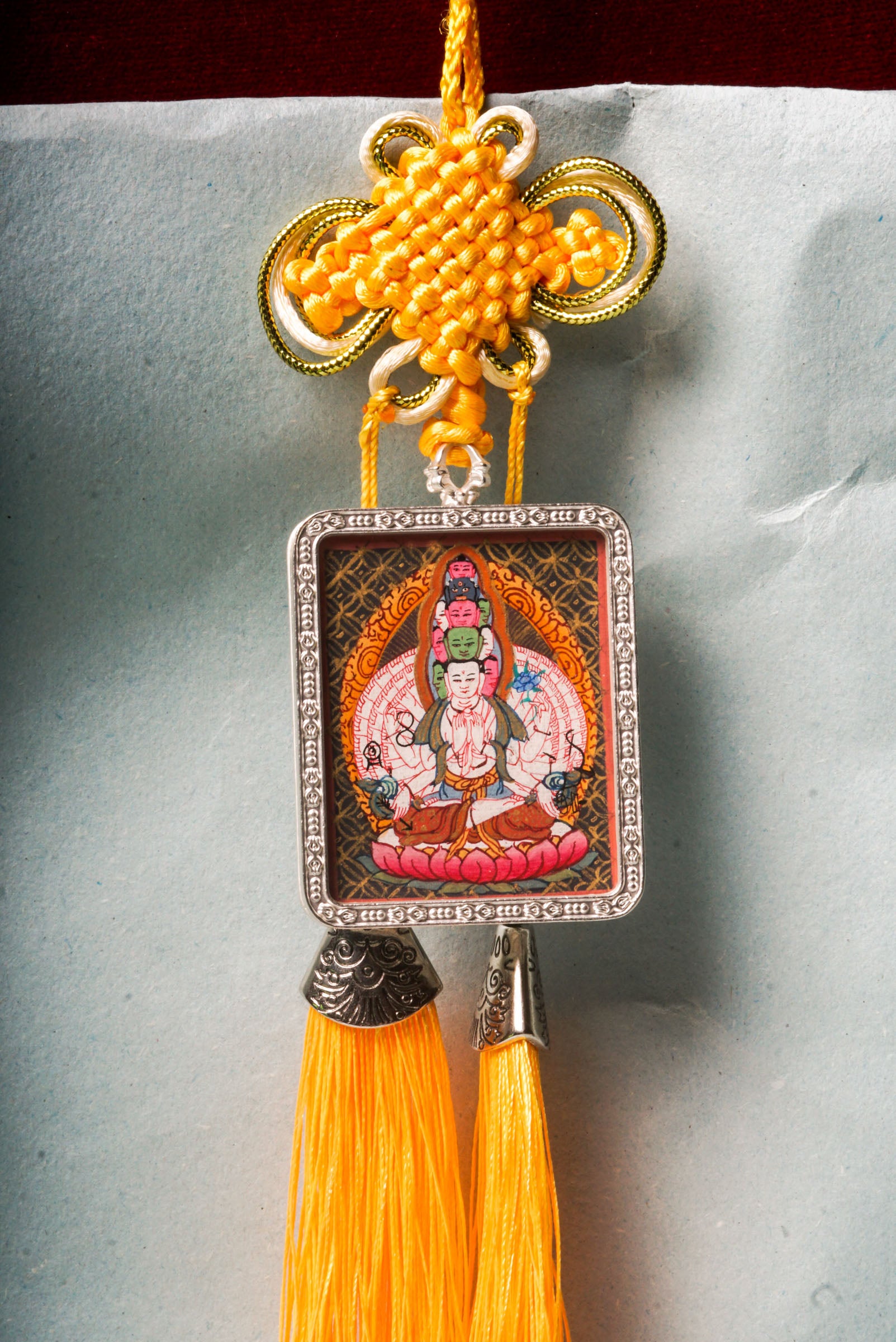 The Avalokiteshvara Ghau Thangka depicts the compassionate Bodhisattva with multiple arms and heads, symbolizing his boundless ability to help all beings. Hand-painted with natural pigments, this portable Thangka serves as a powerful amulet for protection, guidance, and spiritual growth.