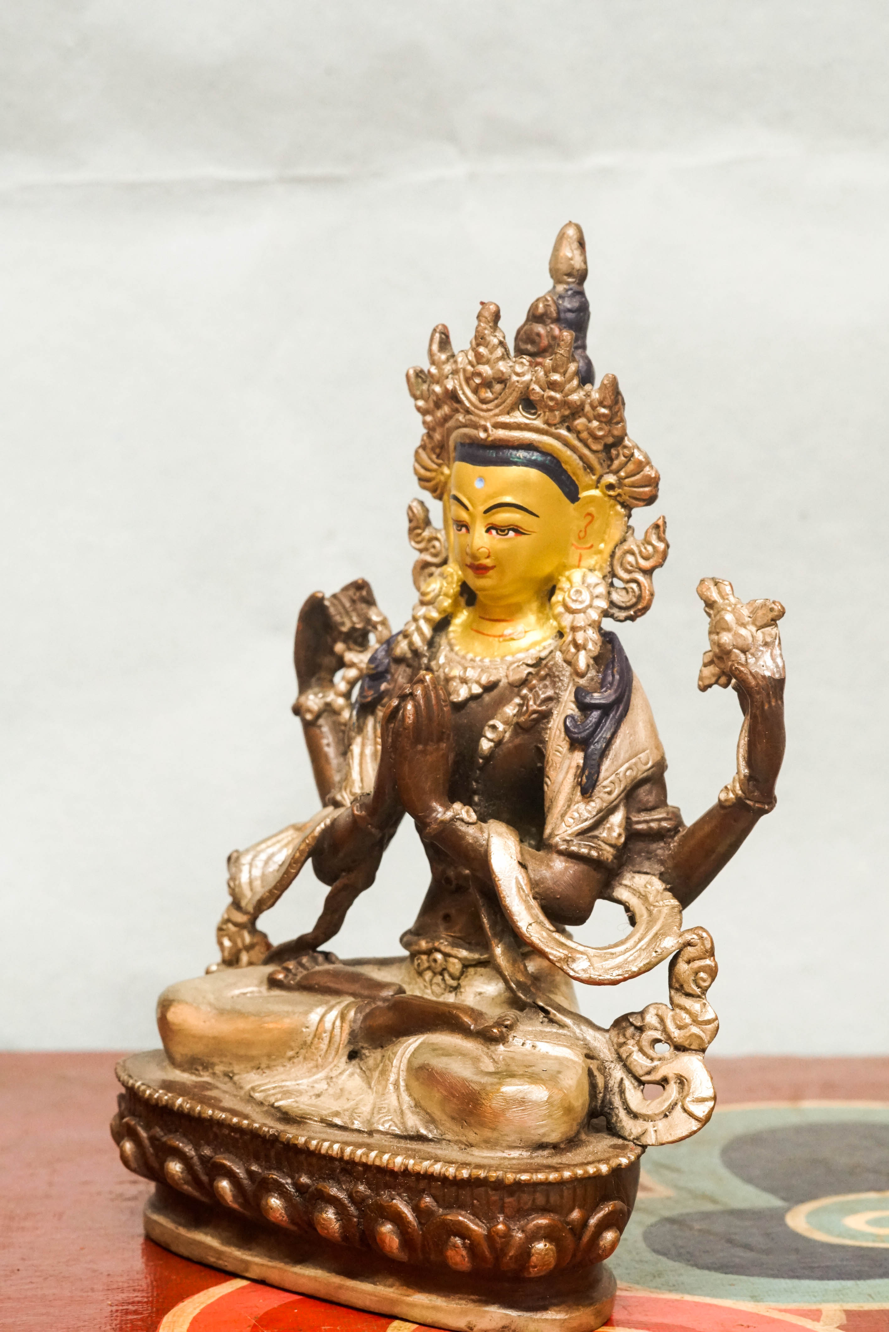 Chenrezig statue seated on a lotus base, holding a lotus flower and prayer beads, embodying compassion and spiritual guidance