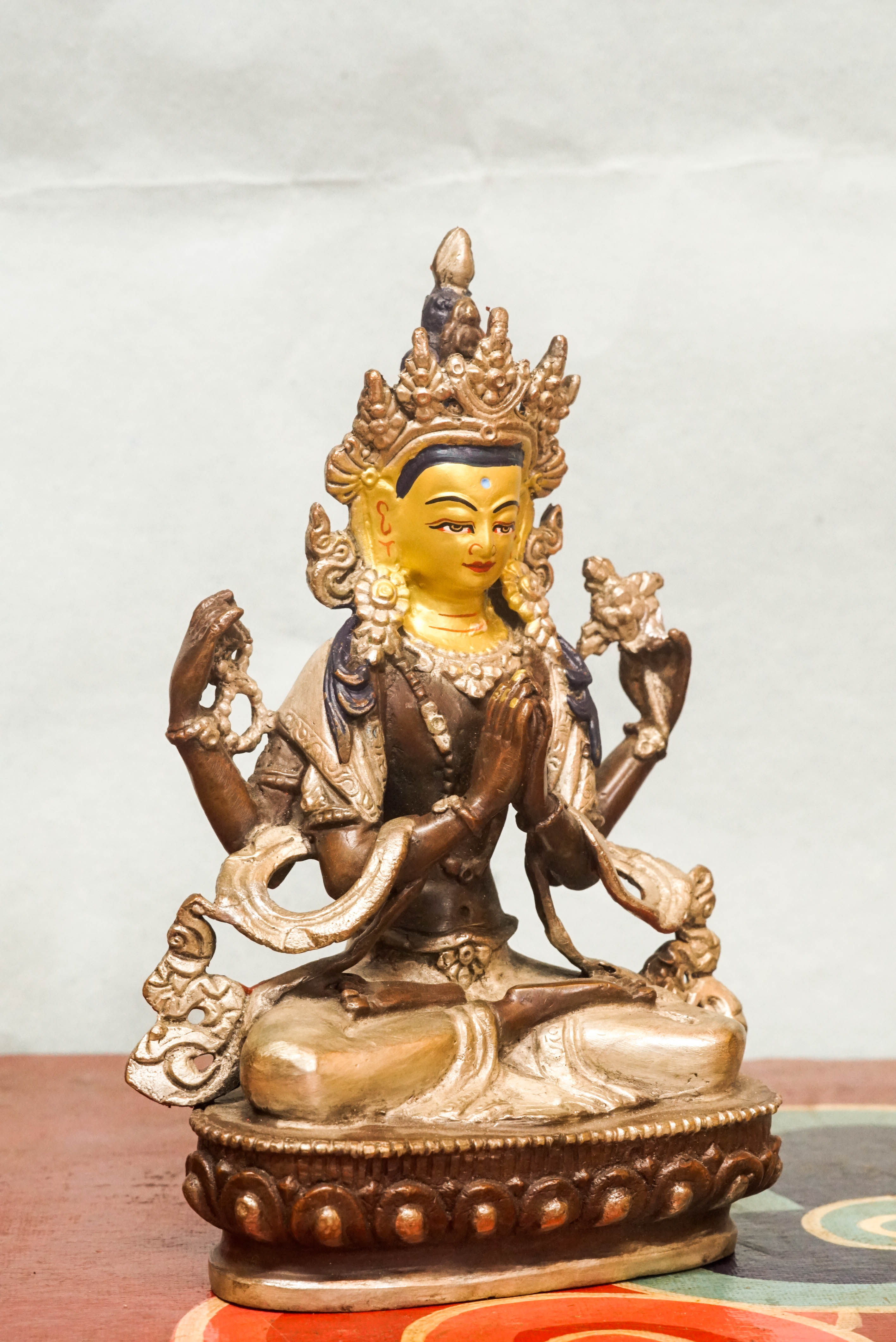 Chenrezig statue seated on a lotus base, holding a lotus flower and prayer beads, embodying compassion and spiritual guidance