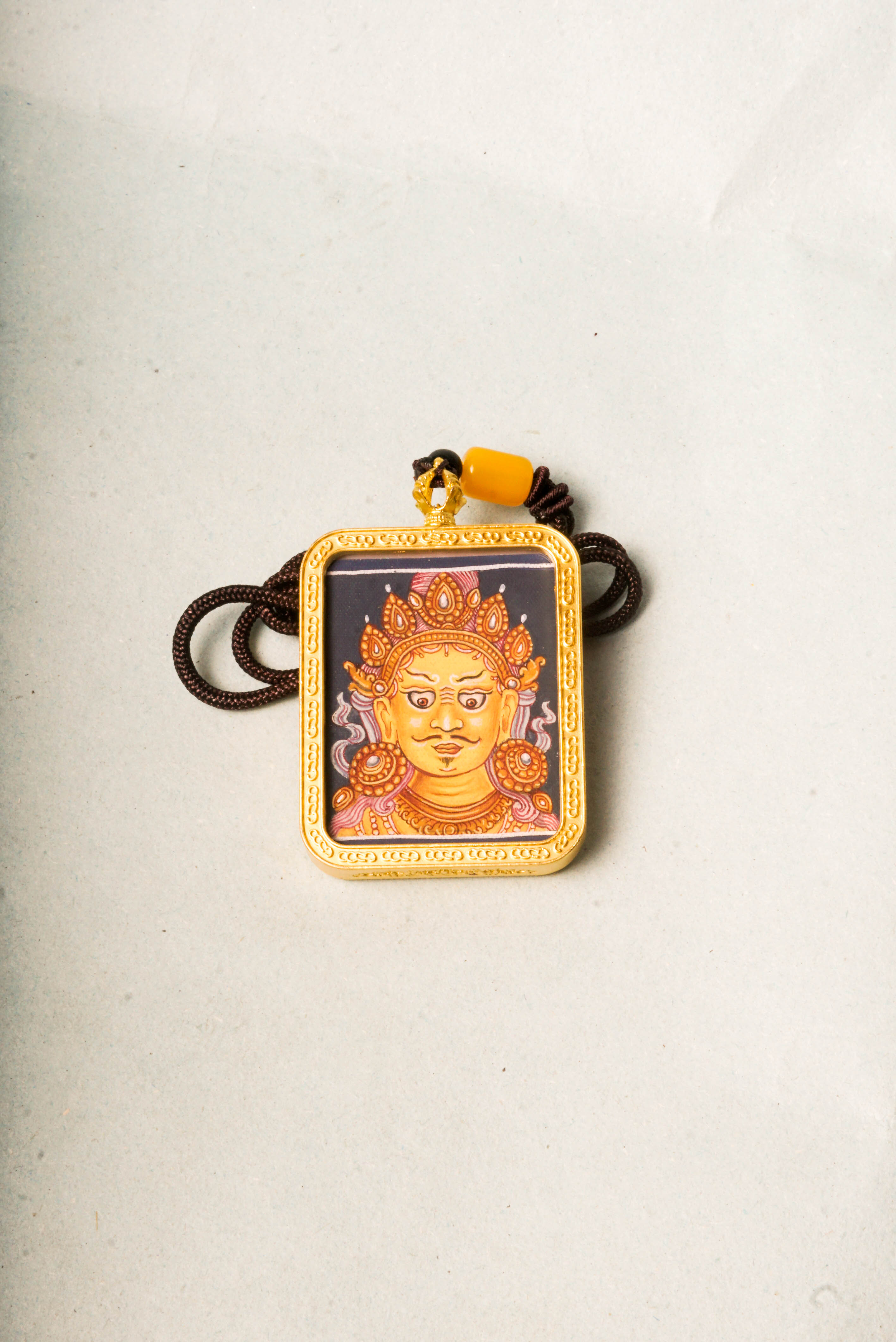 This Newari Zambala Ghau Thangka depicts the Tibetan Buddhist god of wealth holding a jewel-spouting mongoose, symbolizing prosperity and protection. Handcrafted in vibrant Newari style, it's ideal for personal altars or as a spiritual amulet.