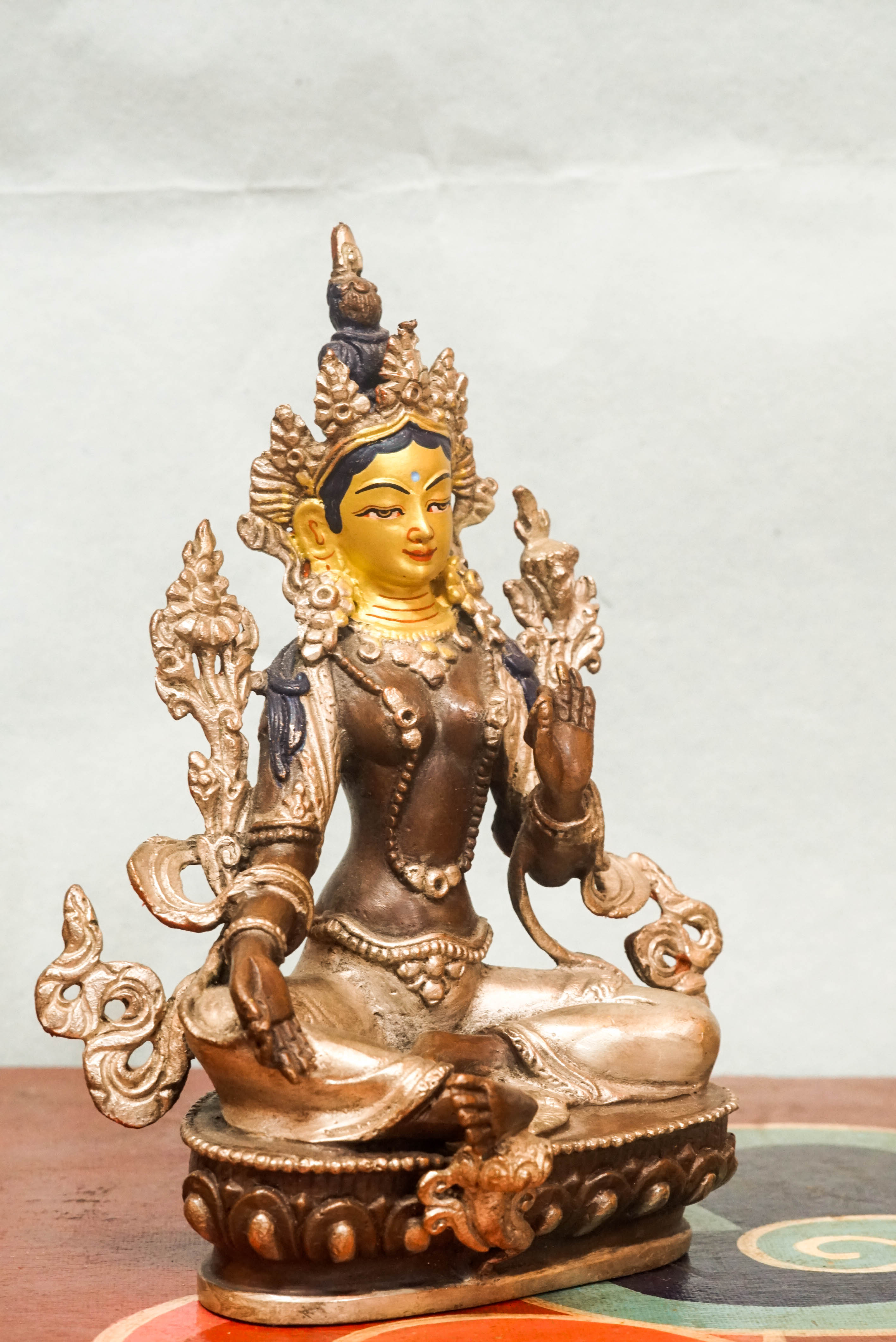 Statue of Green Tara, the female Bodhisattva of compassion and protection, seated with one leg extended, symbolizing her readiness to respond to suffering.