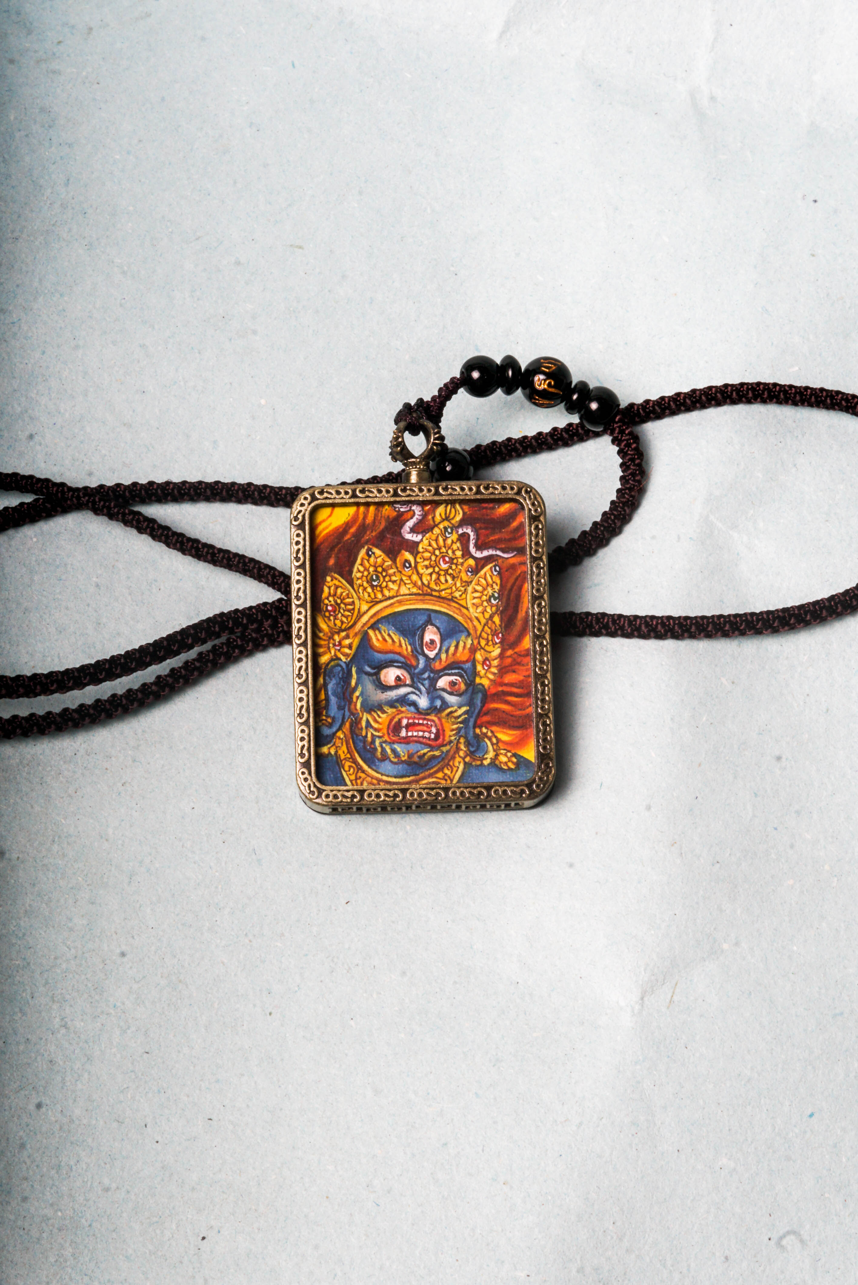 Mahakala is a fierce protector in Tibetan Buddhism, embodying the power to remove obstacles and safeguard spiritual practice. This hand-painted Mahakala Ghau Thangka serves as a portable shrine, channeling his transformative energy through vibrant traditional Tibetan artistry.