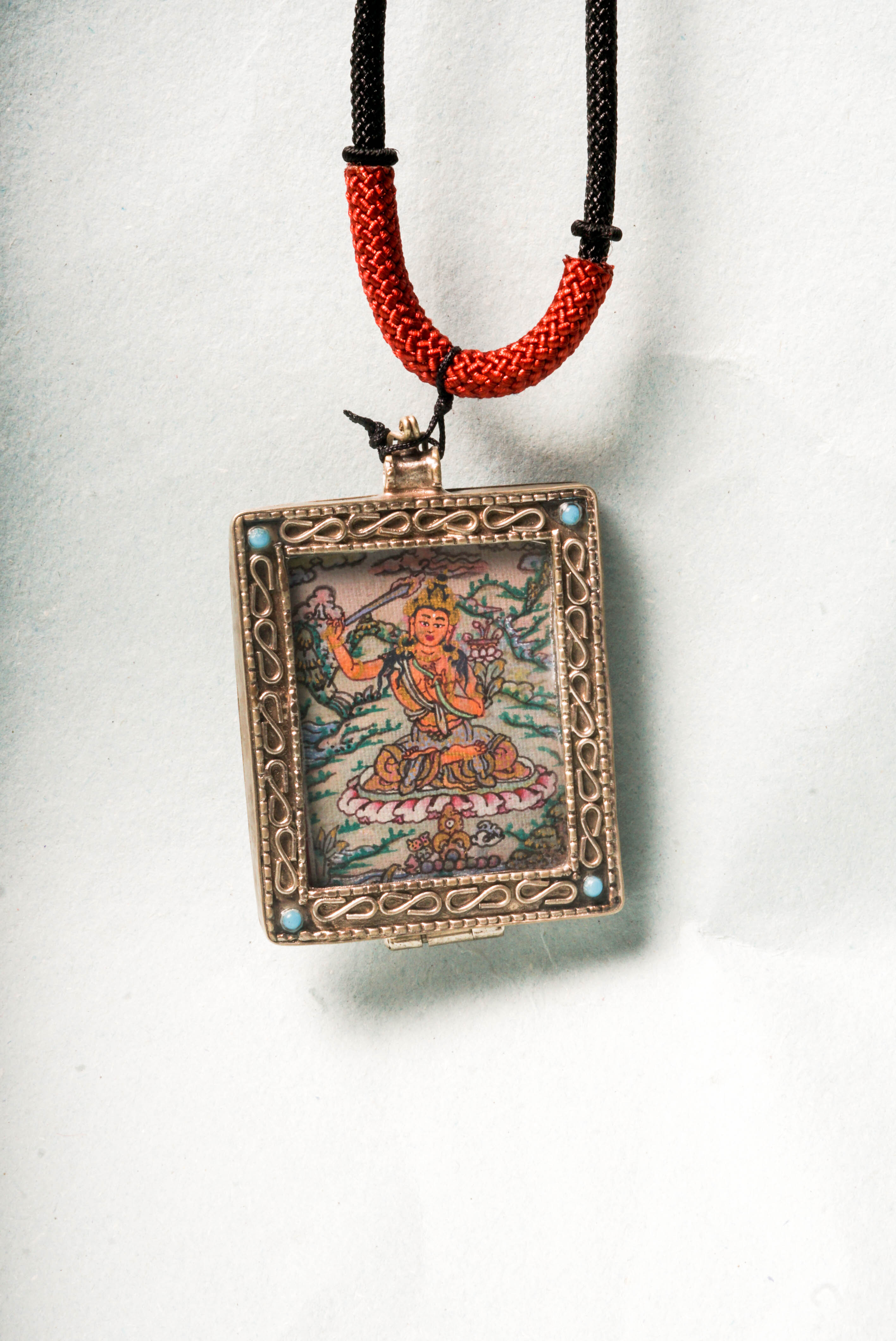 The Manjushri Ghau Thangka depicts the Bodhisattva of Wisdom, symbolizing clarity and insight. Hand-painted in a portable shrine format, it features his iconic sword and scripture, aiding in meditation and the pursuit of spiritual knowledge.