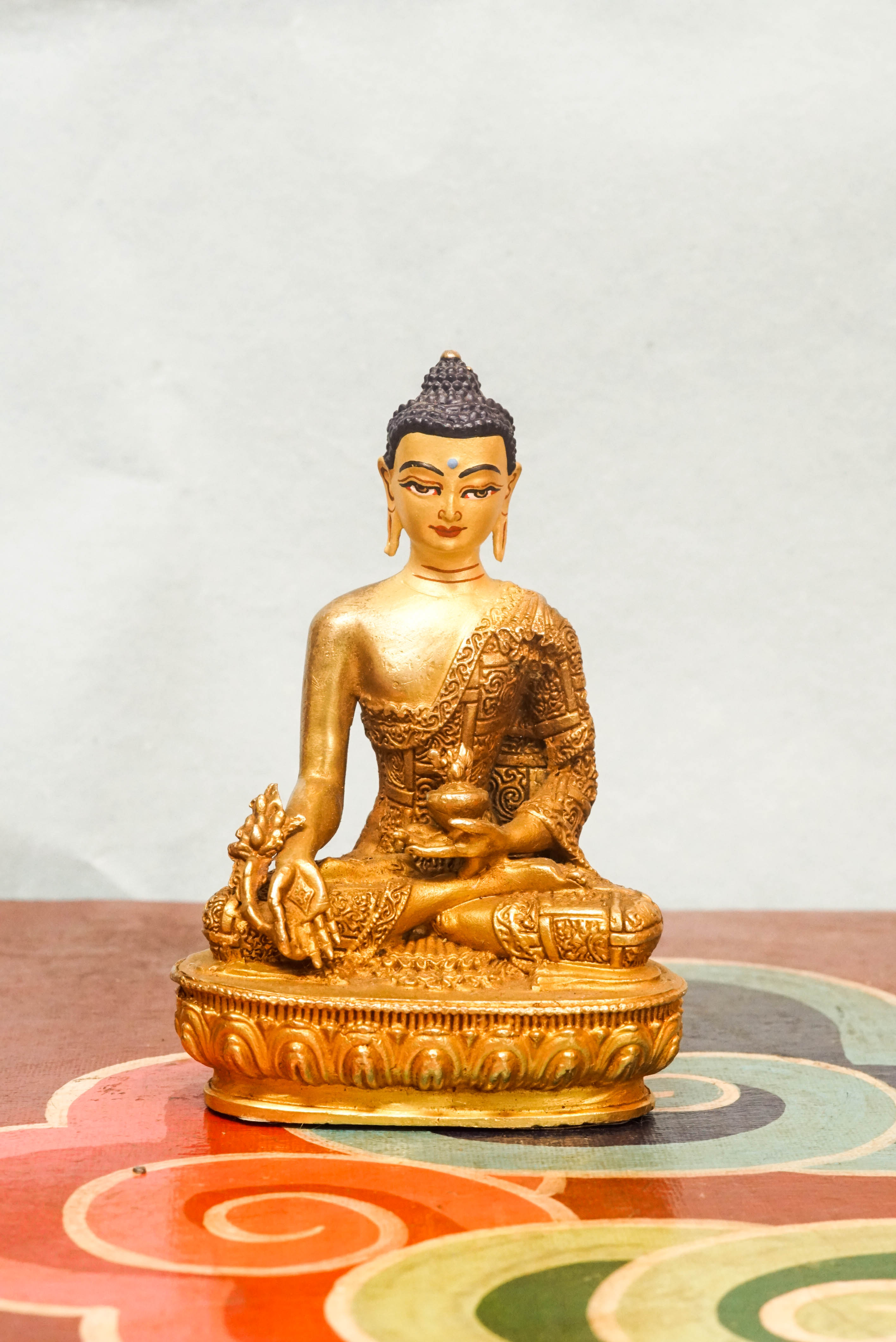Handcrafted Medicine Buddha statue with fully opened eyes, holding a healing bowl, surrounded by a radiant lapis aura, seated on a lotus pedestal.